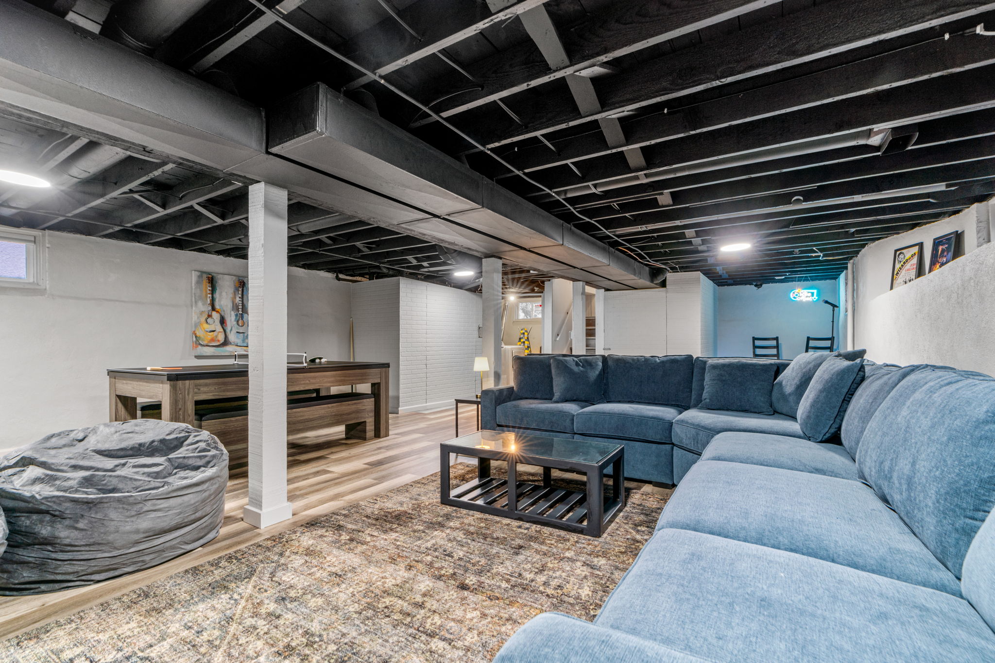 A modern and inviting basement space featuring a blue sectional sofa and game table.