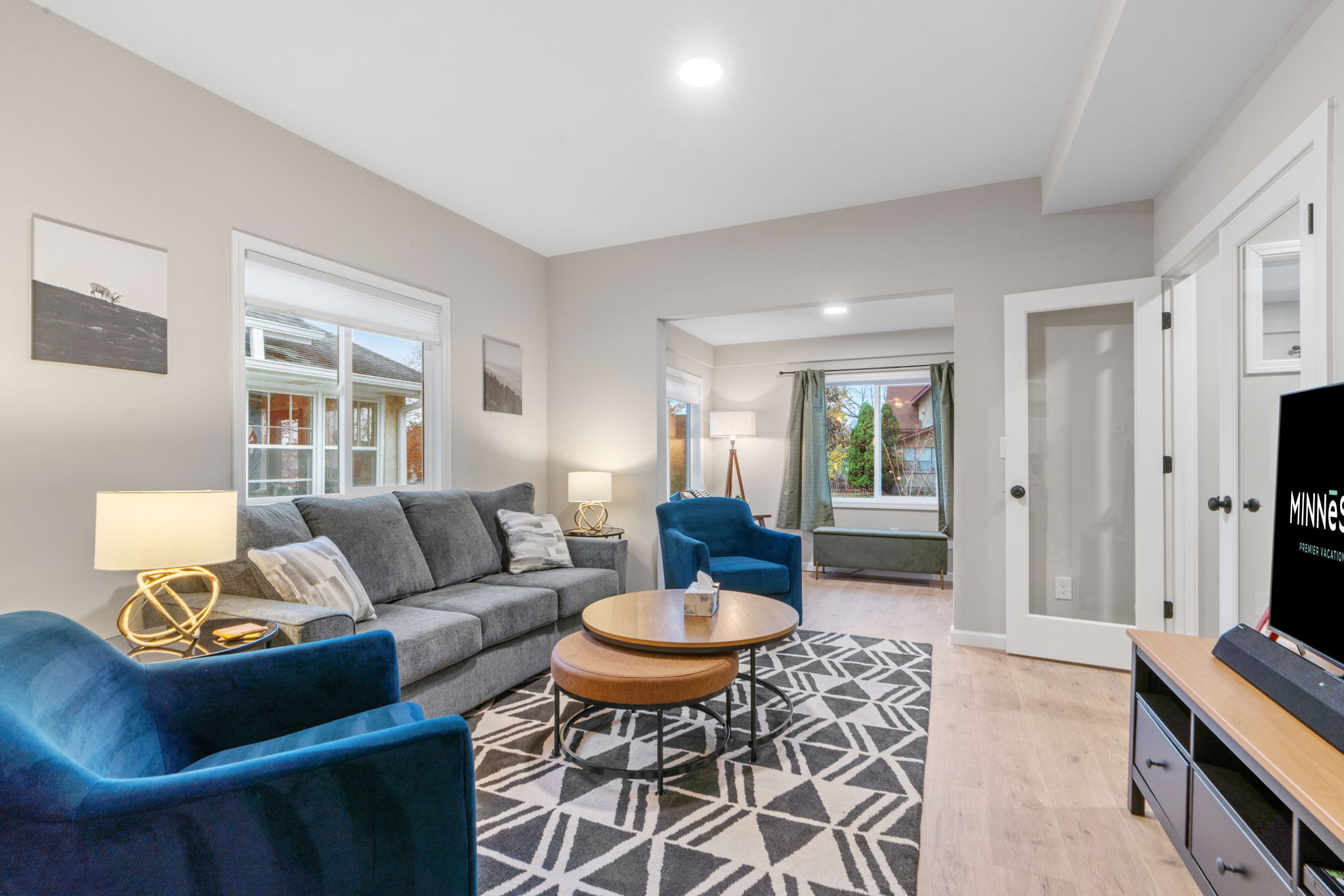 Inviting living room with grey sofa and blue chairs, featuring a coffee table and stylish decor.