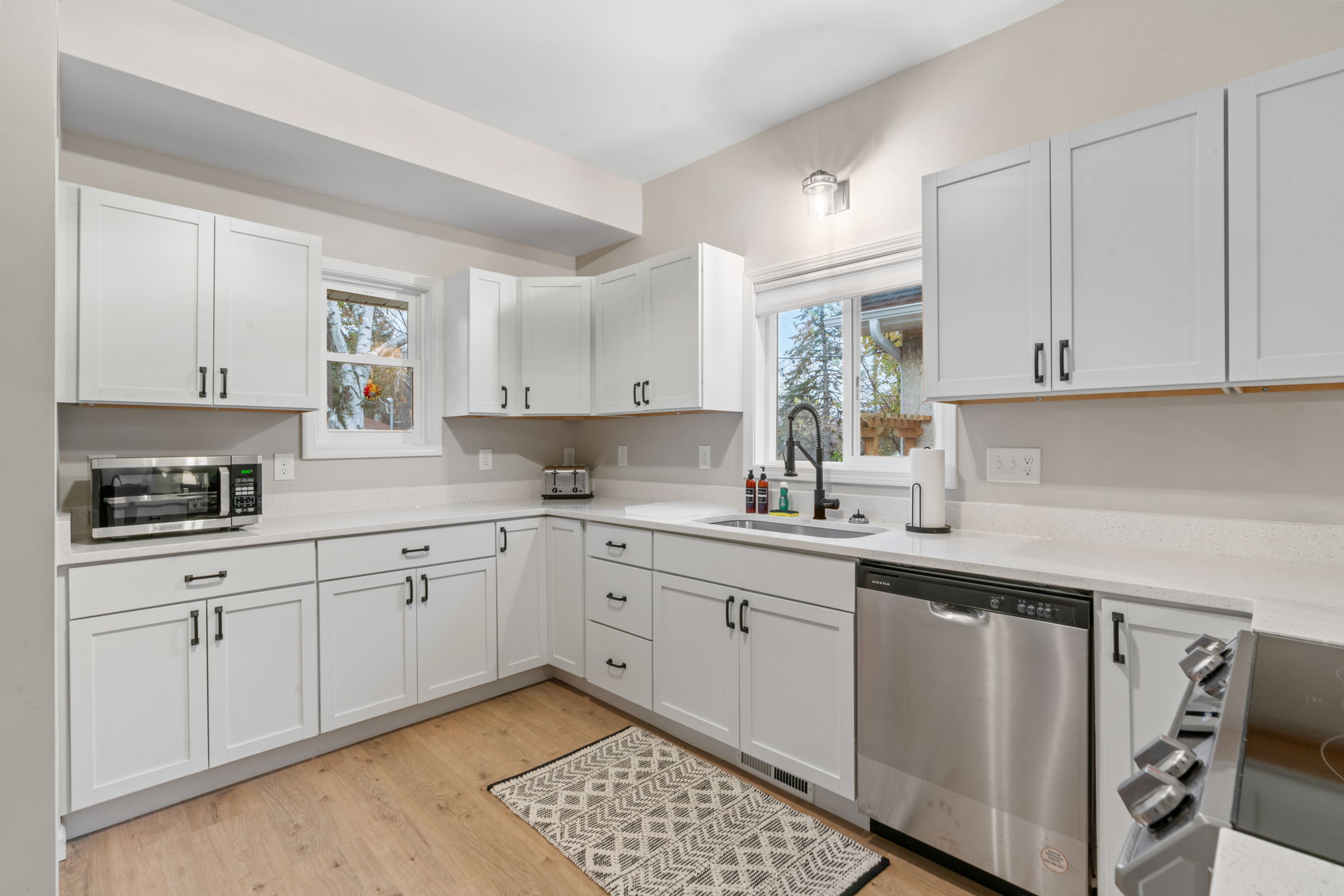 Bright and modern kitchen with white cabinetry and stainless-steel appliances.