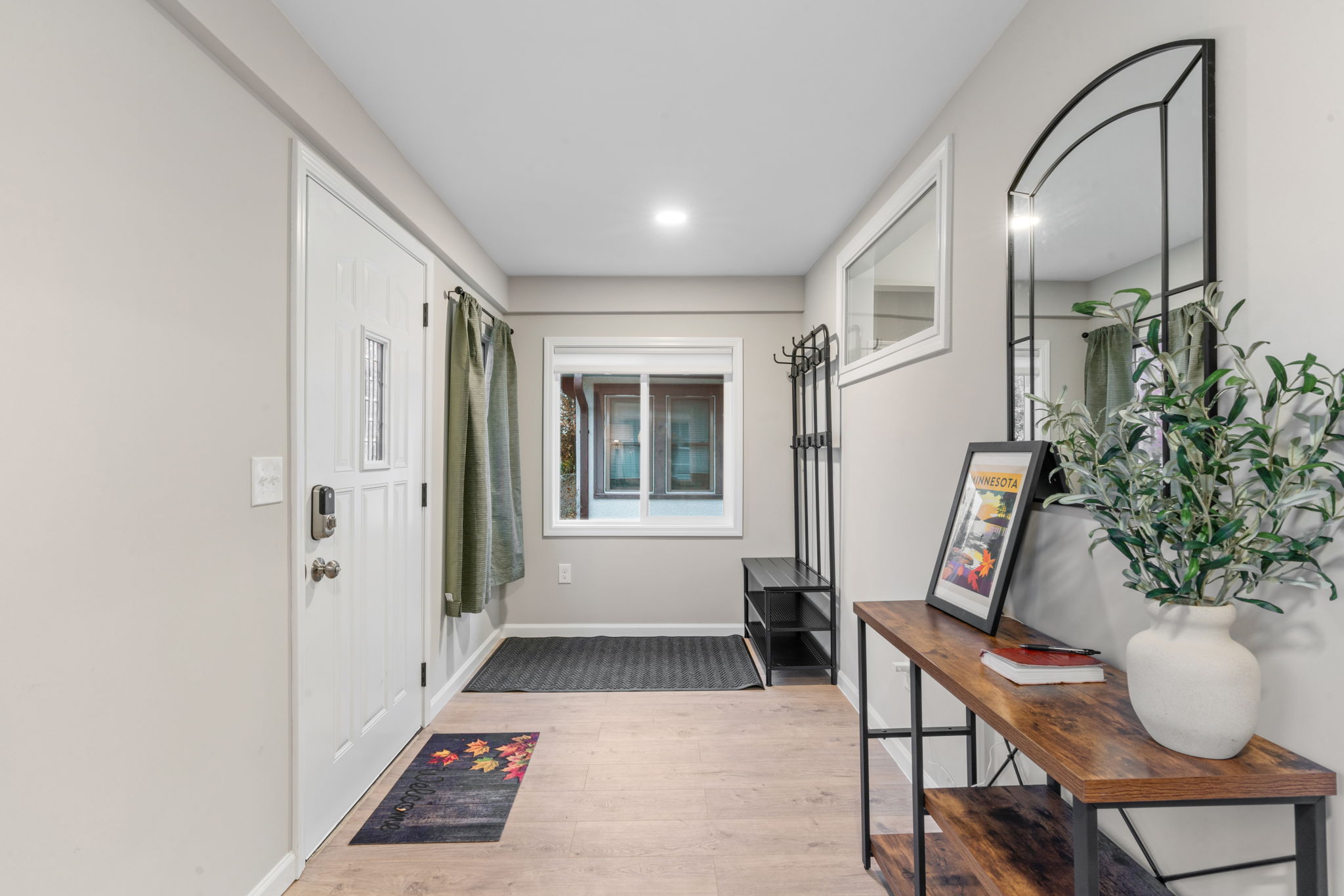 A modern and welcoming entryway featuring a white front door and stylish decor.