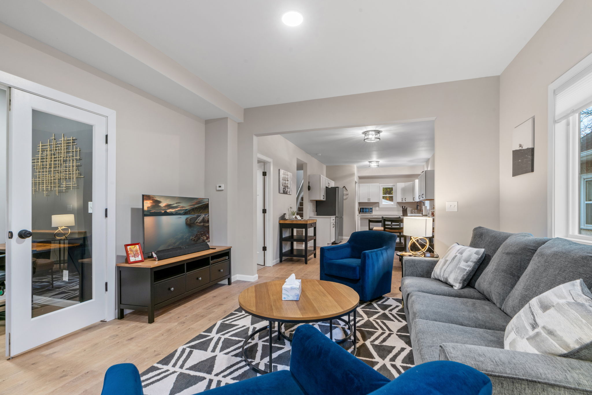A modern living room featuring stylish furniture and an open layout connecting to the kitchen.