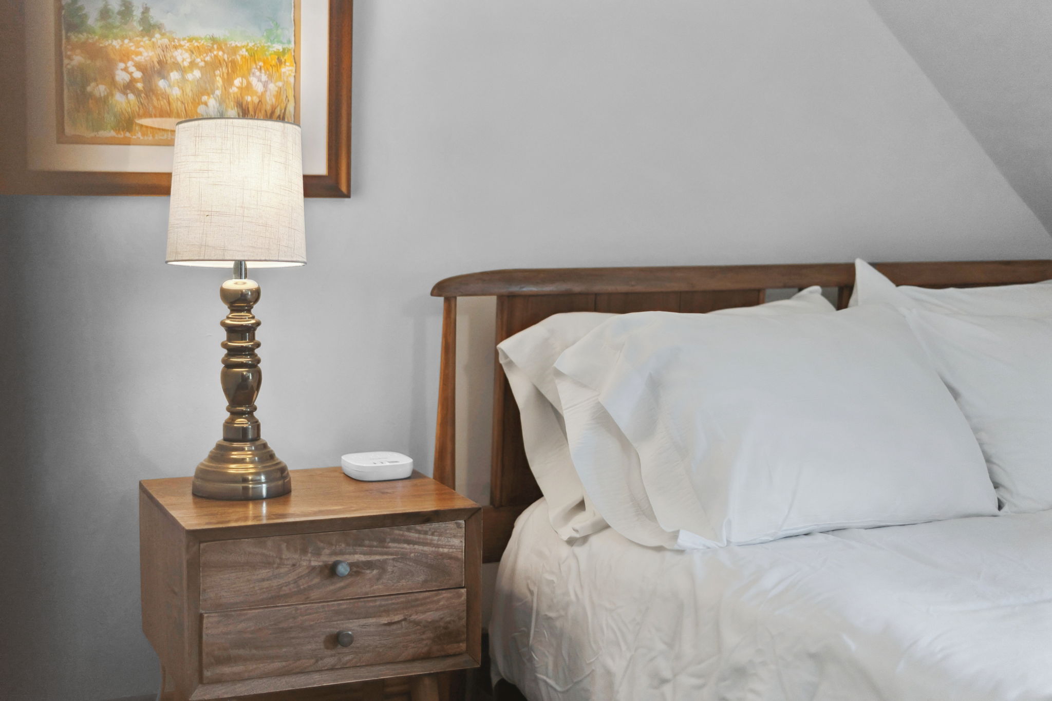 A cozy bedroom corner with a wooden nightstand and a glowing lamp.