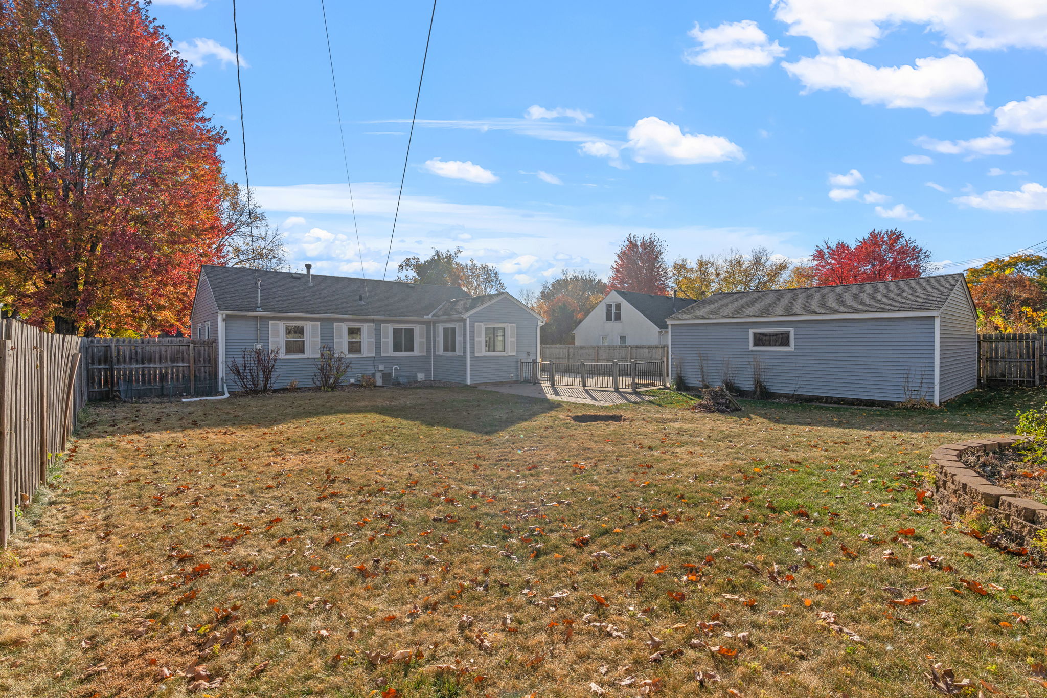 A picturesque autumn backyard featuring a charming blue house and vibrant foliage.