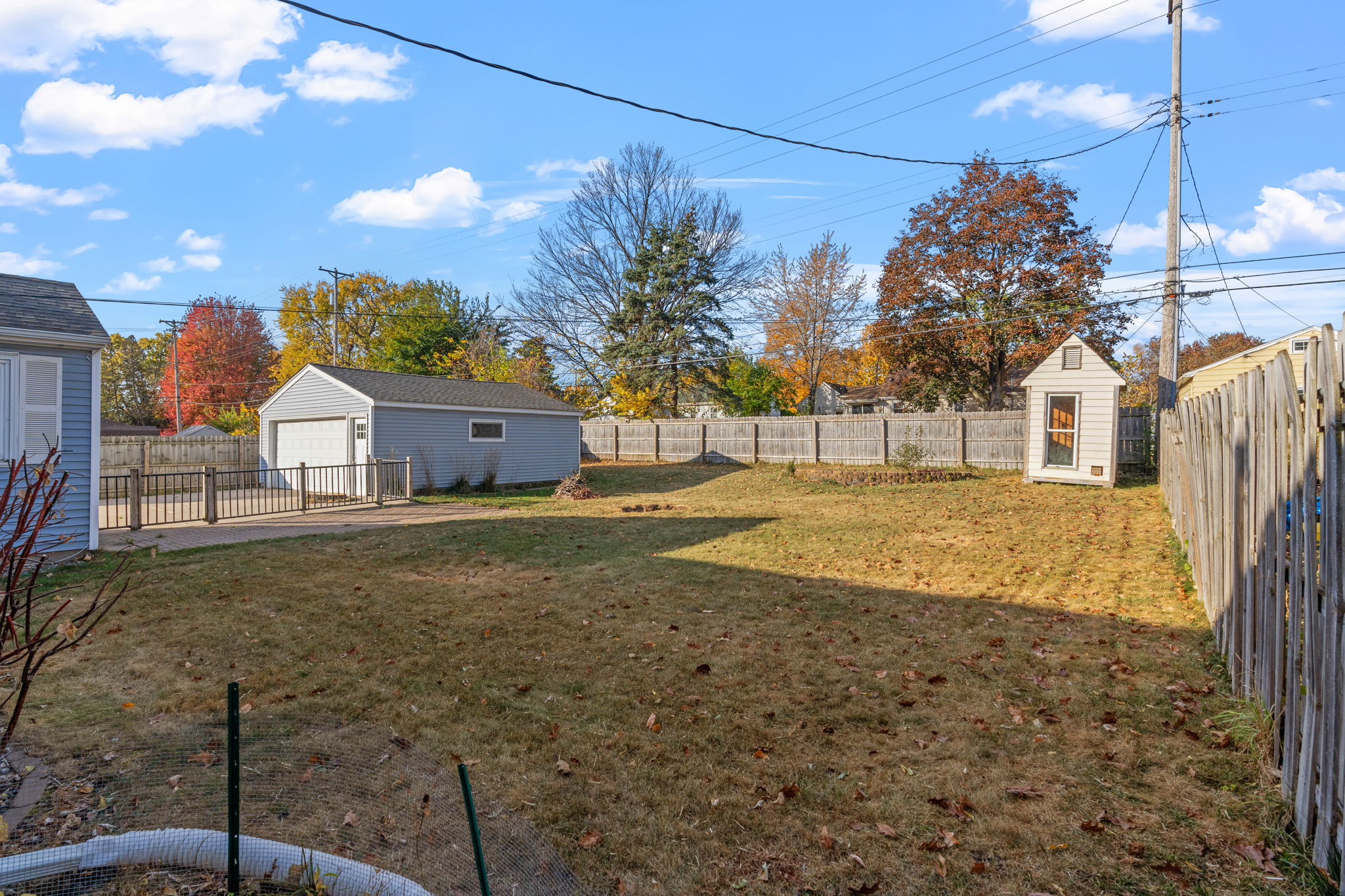 A serene autumn backyard with a garage and shed.