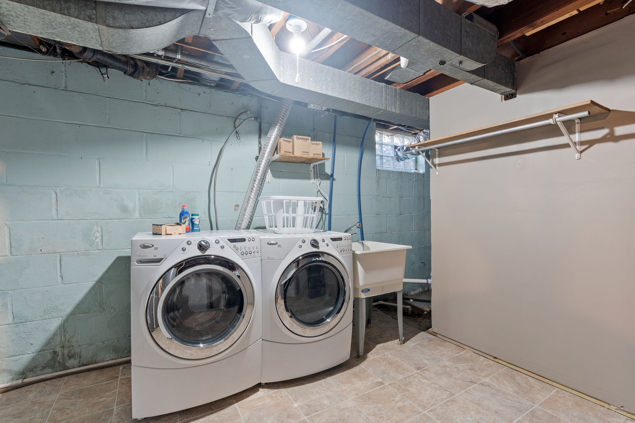 A functional basement laundry area with modern appliances and practical storage.