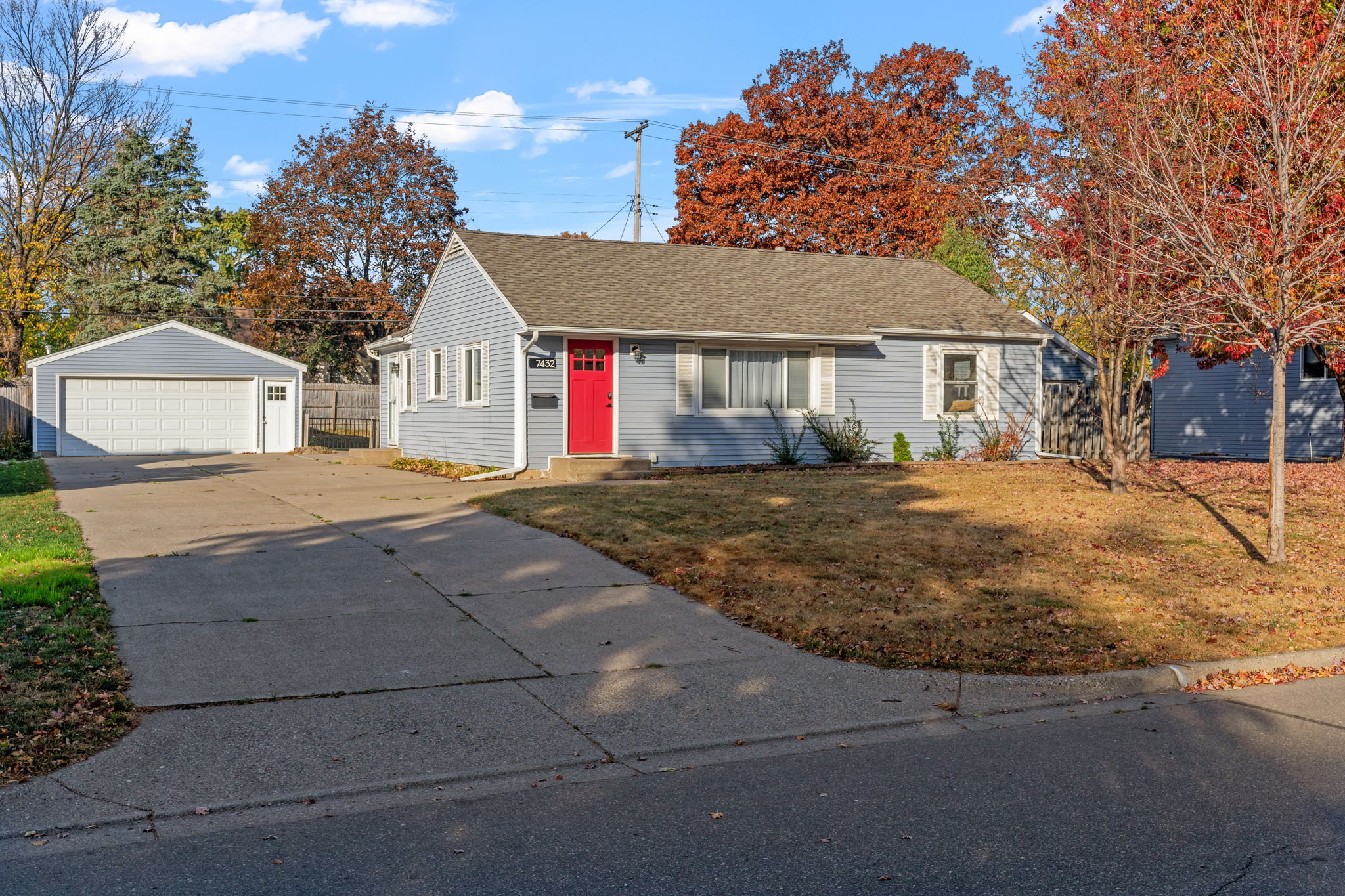 Charming blue house with red door set in an autumn landscape.