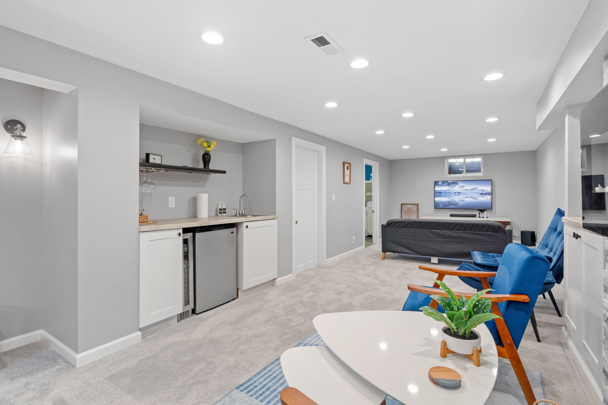 A modern and cozy basement living space featuring a bar area and lounge seating.