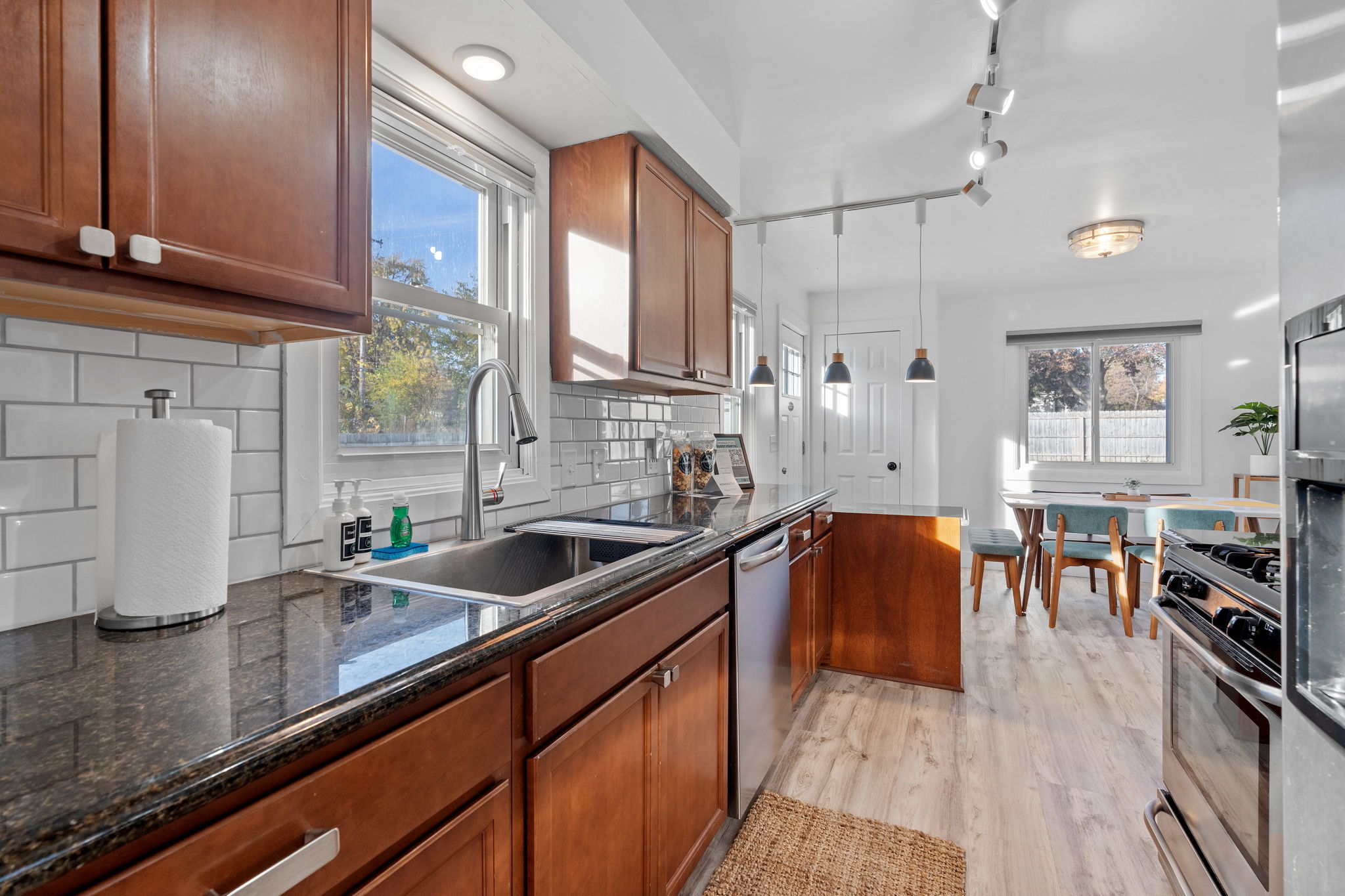 Modern kitchen featuring a blend of dark granite countertops and wooden cabinets, with ample natural light.