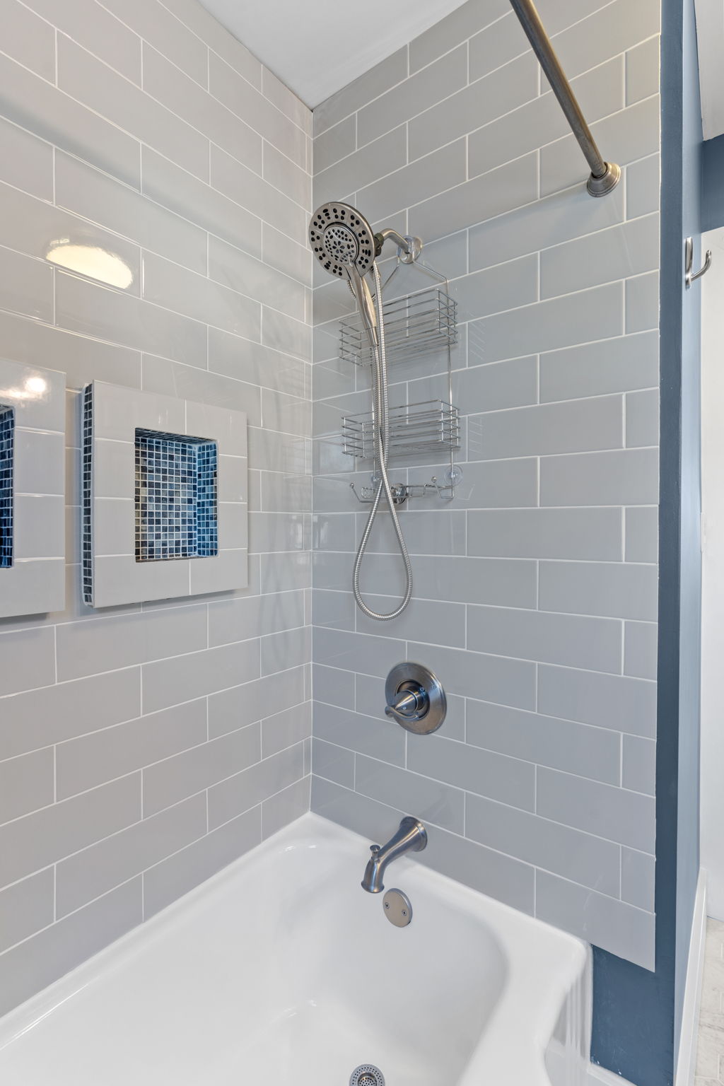 Stylish modern shower area with light gray tiles and a unique blue mosaic detail.