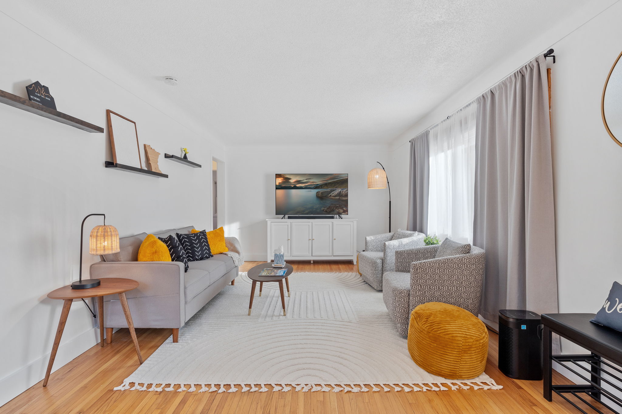 A cozy and modern living room featuring a gray sofa, patterned chairs, and stylish decor.