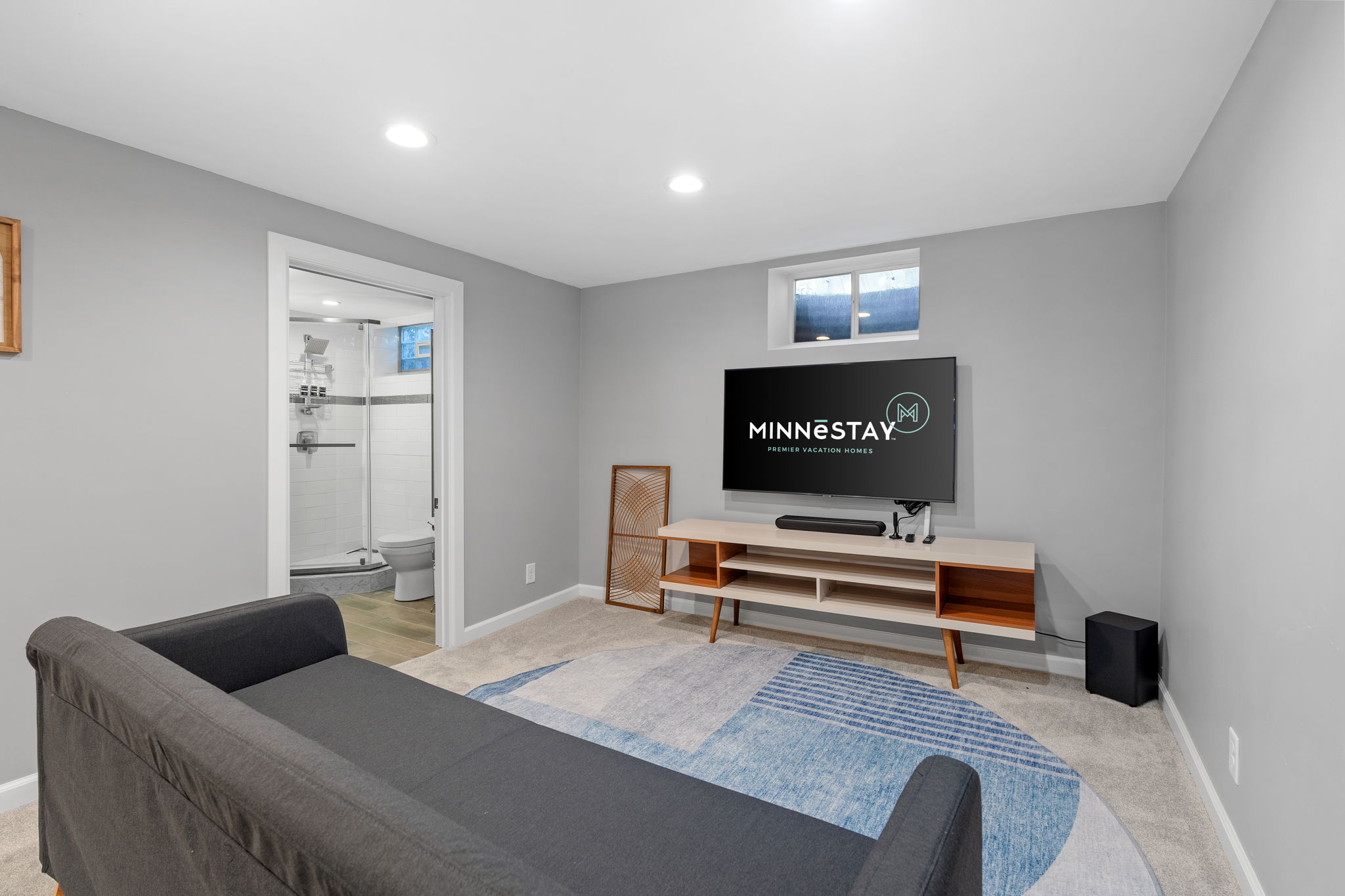 A cozy living room with modern furnishings and a bathroom adjacent to it.