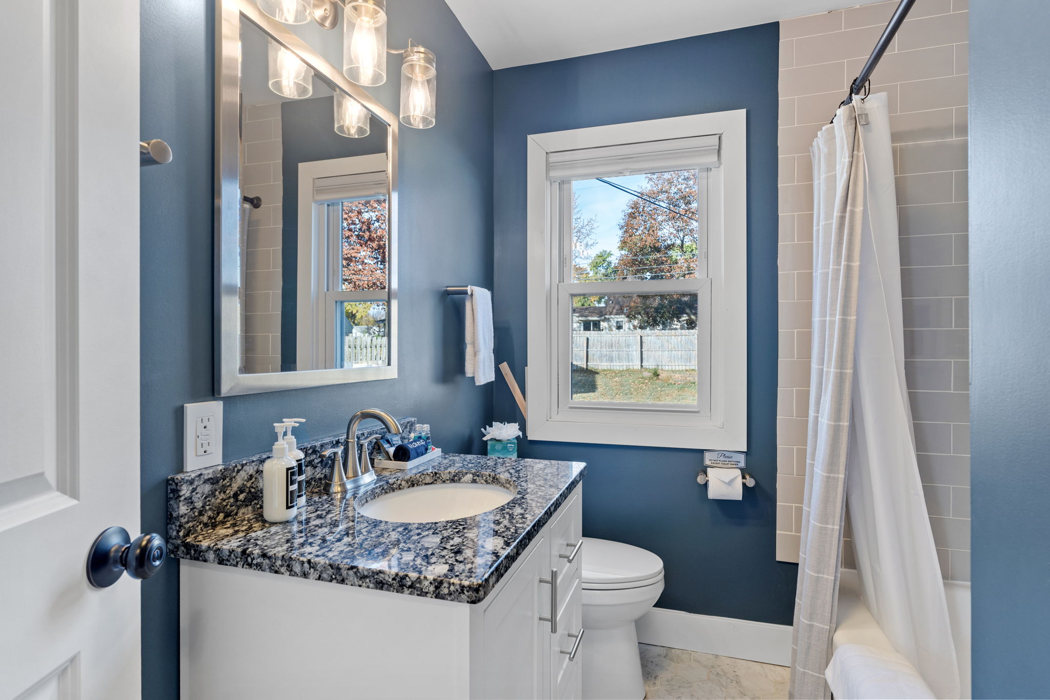 Modern bathroom with navy blue walls and stylish features.