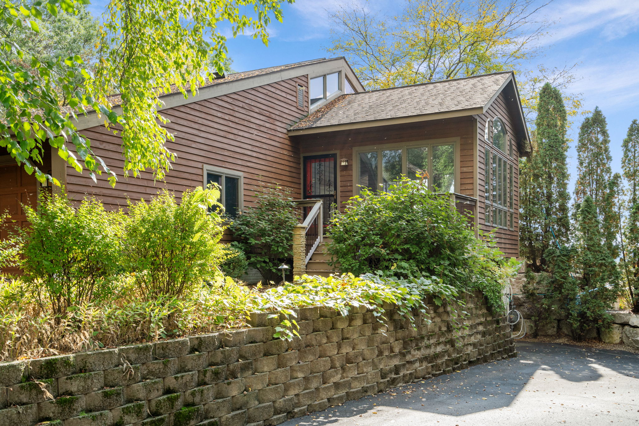 A modern wooden house with lush landscaping and a warm exterior.