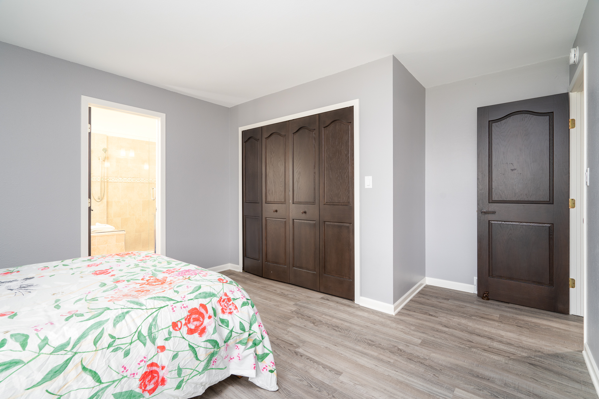 A modern, cozy bedroom featuring a floral quilt and elegant wooden storage.