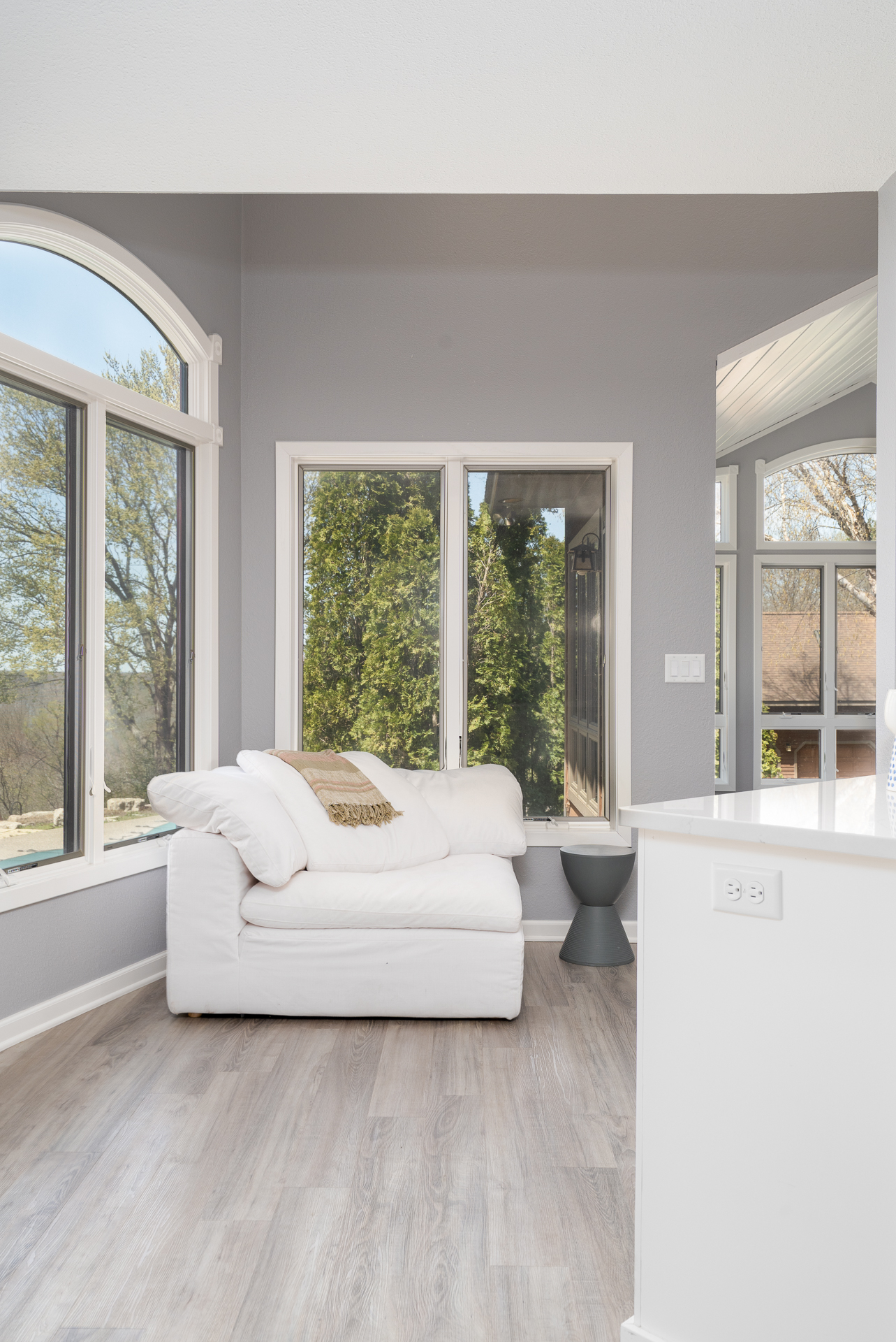 A bright and cozy corner in a modern living space with large windows and a plush white sofa.