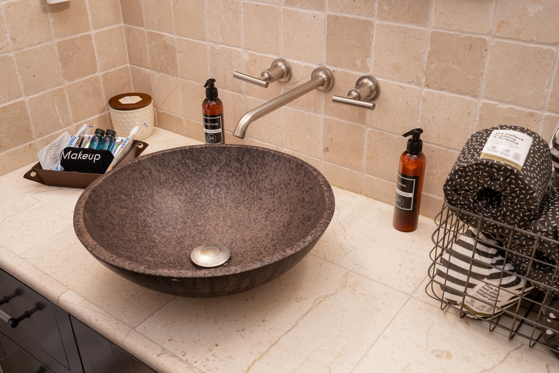 A modern bathroom countertop featuring a unique stone sink and elegant fixtures.