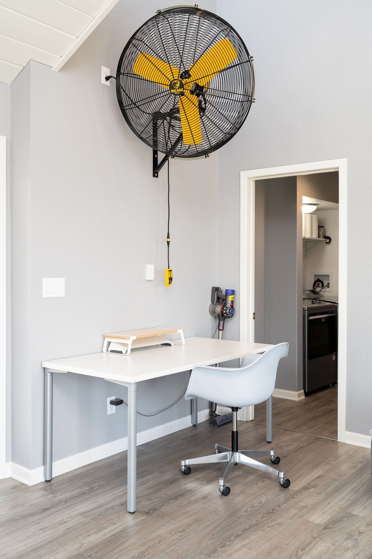 A bright and modern workspace featuring a mounted fan and ergonomic chair.