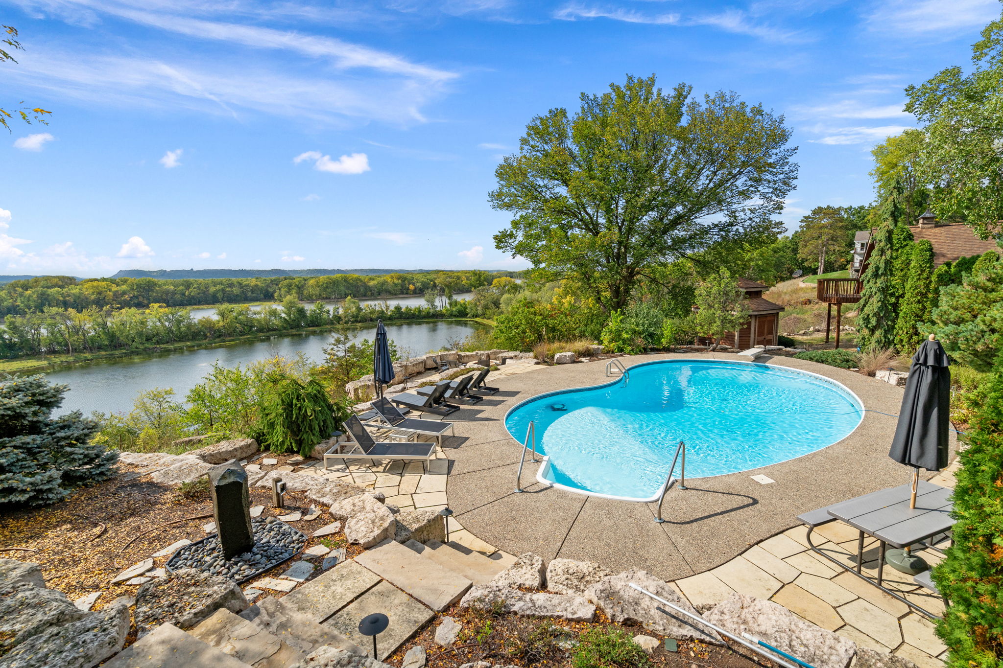 A scenic outdoor pool area with lounges overlooking a river.