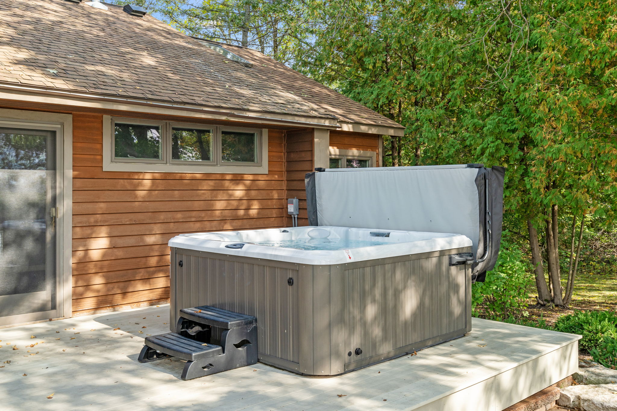 A relaxing hot tub beside a rustic cabin, surrounded by lush greenery.