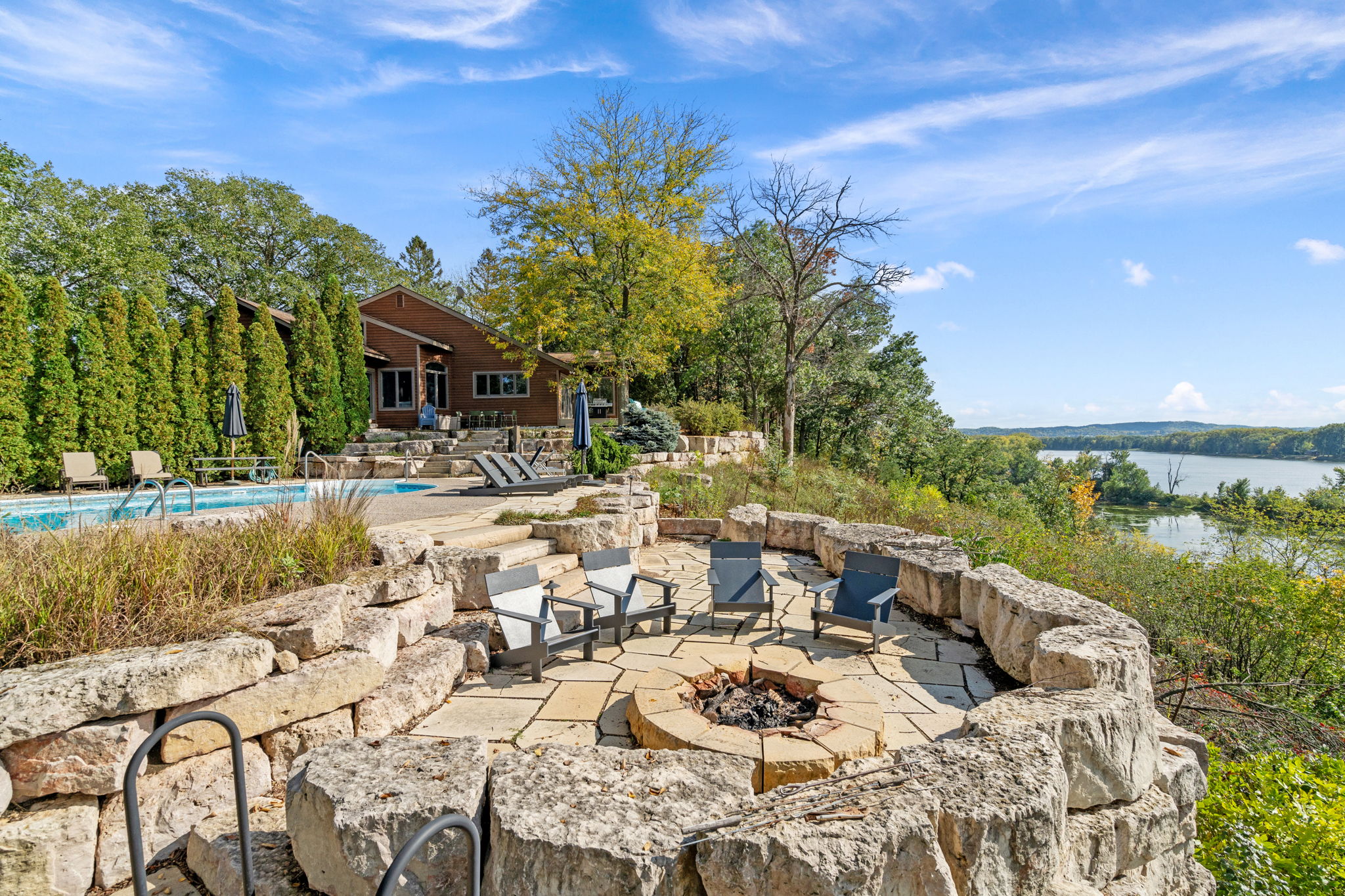 A tranquil outdoor retreat featuring a fire pit, pool, and scenic river view.