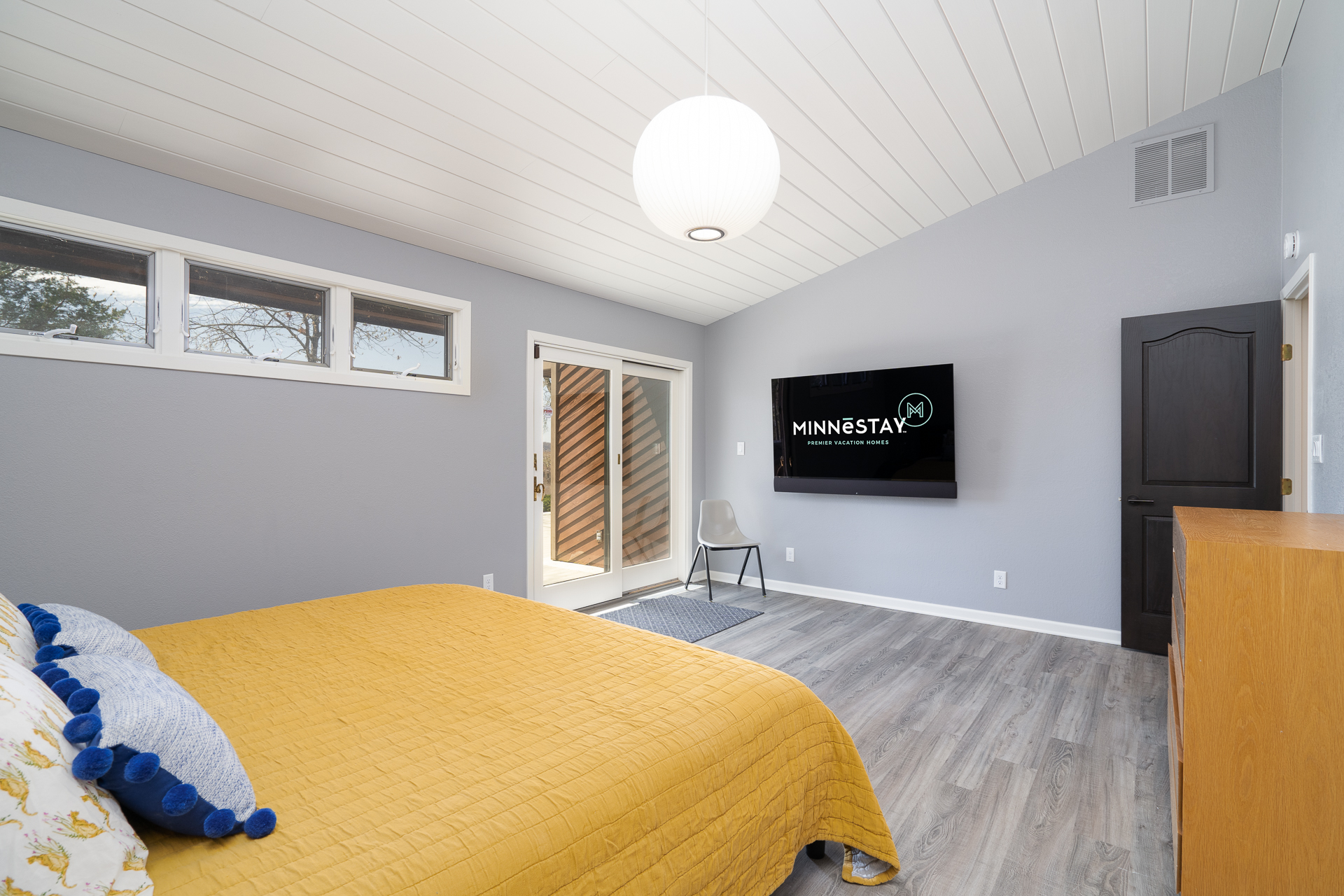Modern bedroom featuring a mustard bedspread and a sleek television setup.