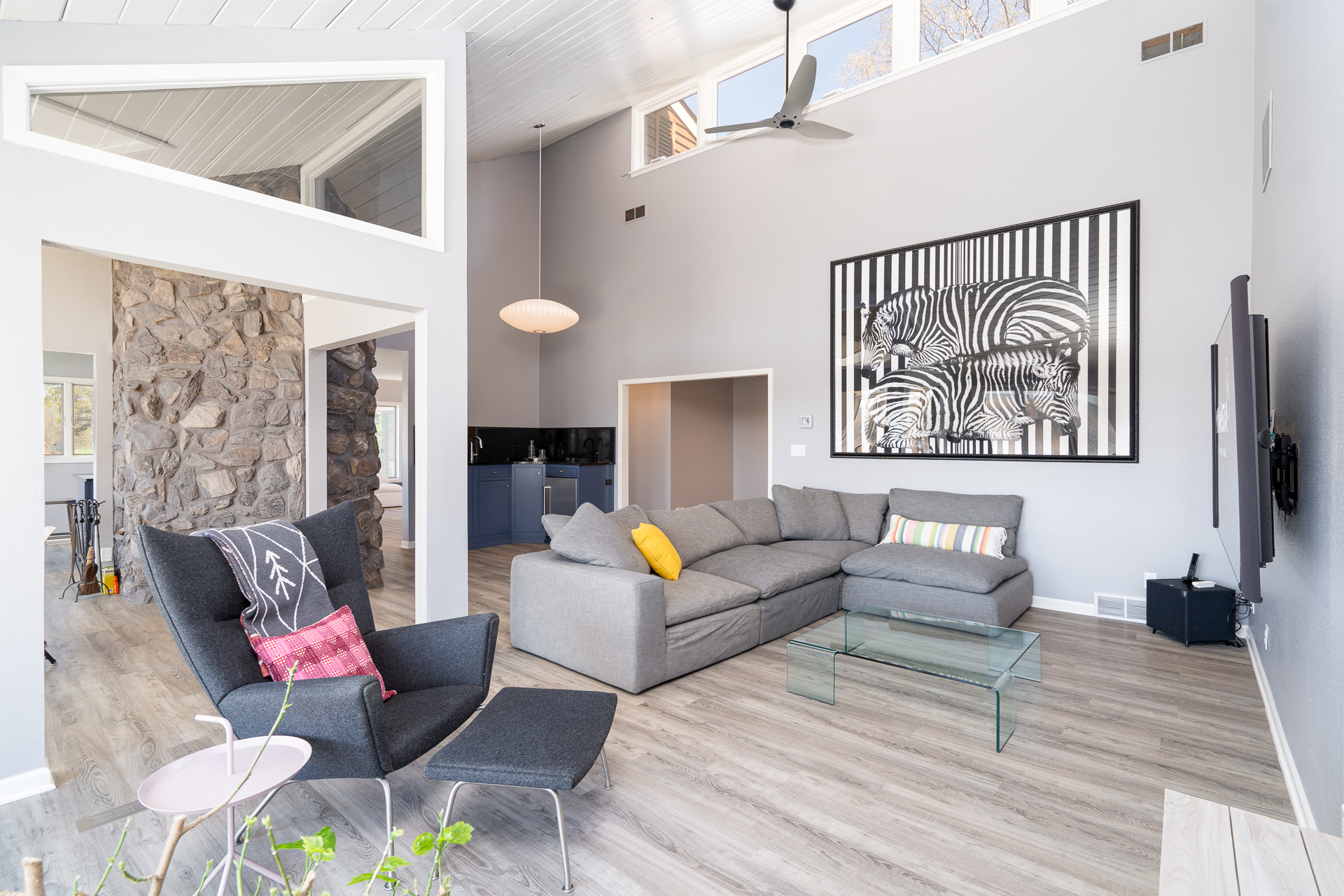 A bright and modern living room featuring a gray sectional sofa and striking zebra artwork.