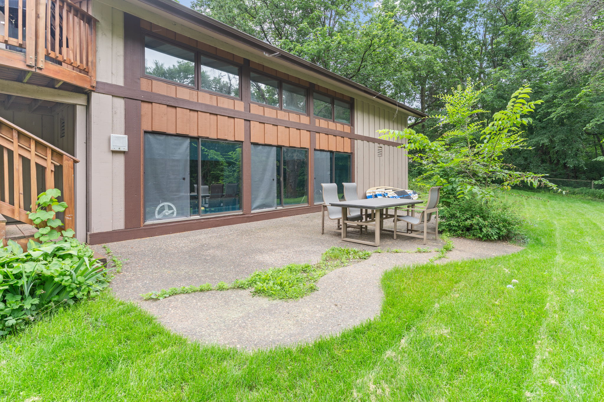 Outdoor patio with seating by a modern home surrounded by greenery.