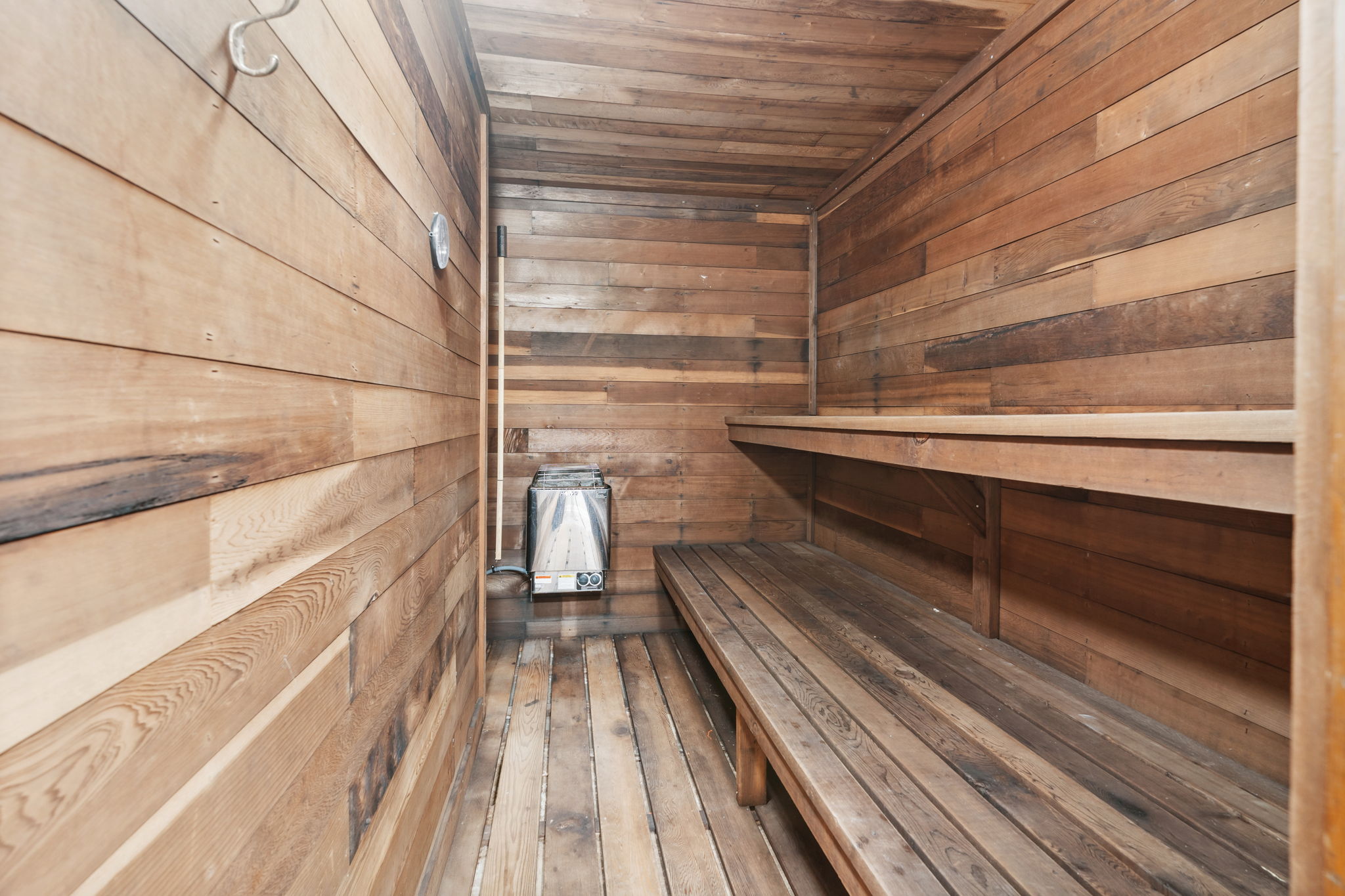 Interior of a cozy wooden sauna with benches and a heater.
