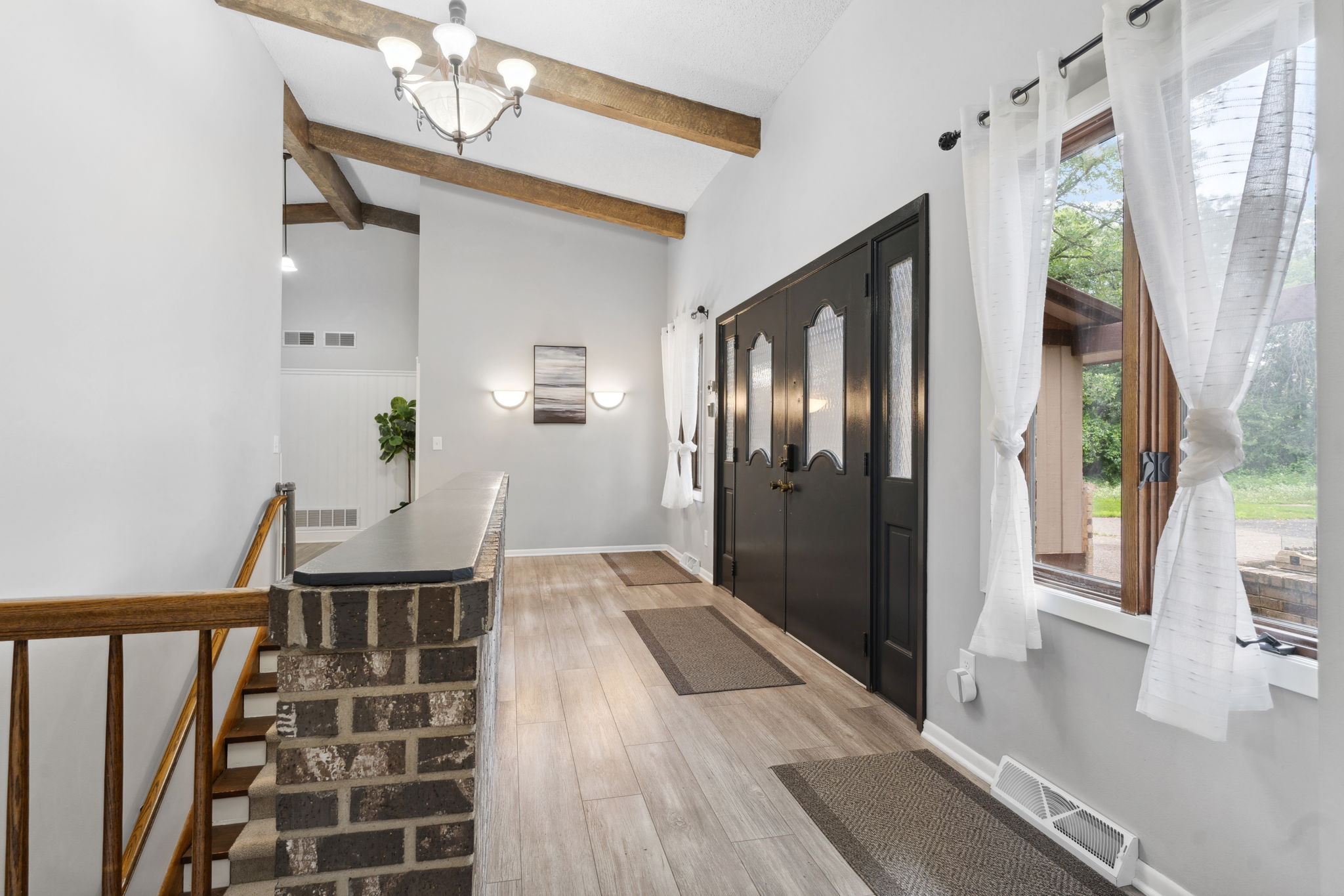 Inviting entryway featuring modern touches and rustic beams.