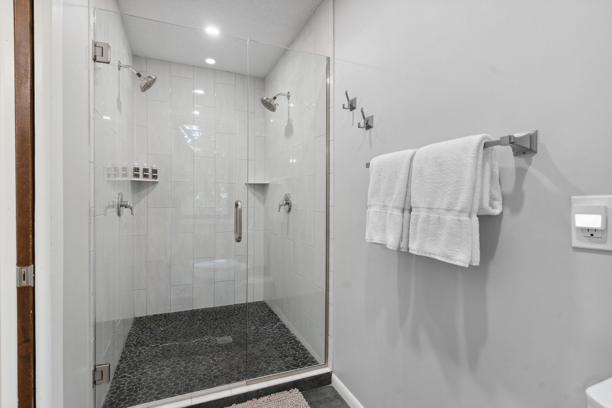 A sleek and modern walk-in shower with pebble stone flooring.