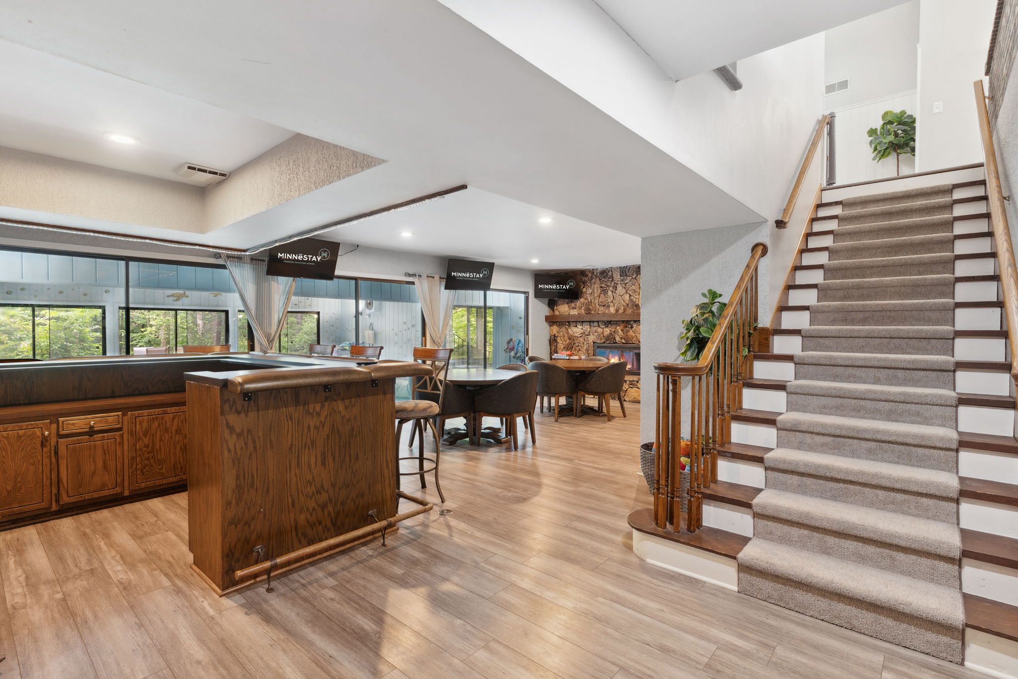 Spacious and inviting living area with a bar, dining space, and staircase.