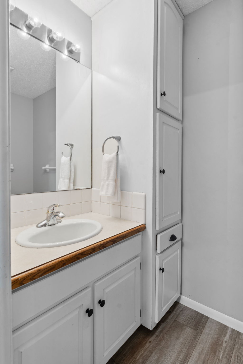 A modern and clean bathroom featuring a white sink, wooden countertop, and elegant towel holder.