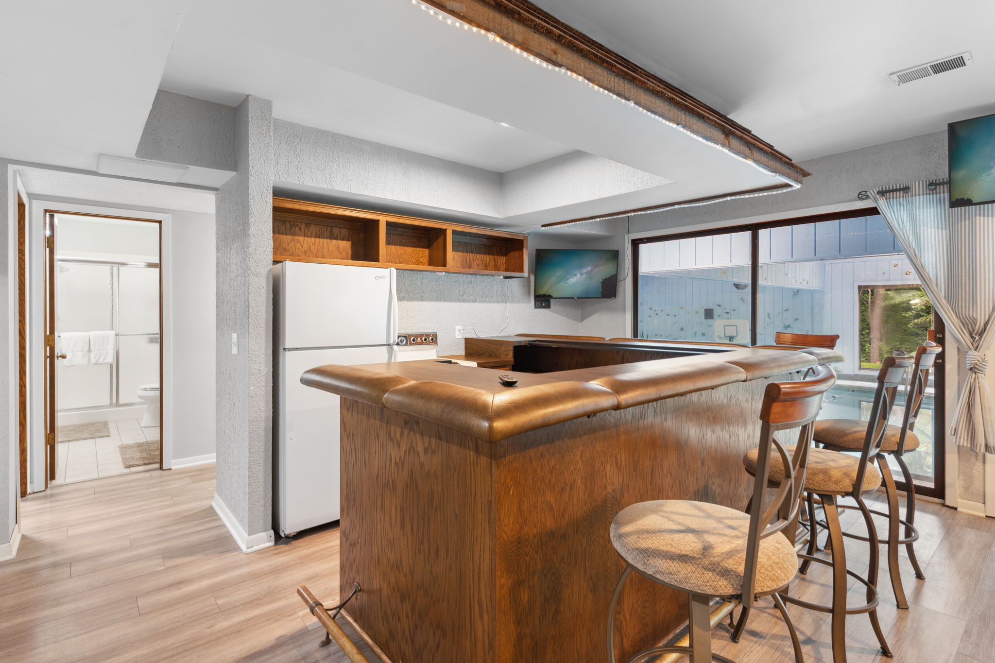 A cozy kitchen bar area with a wooden counter and modern amenities, featuring a sliding bathroom door.