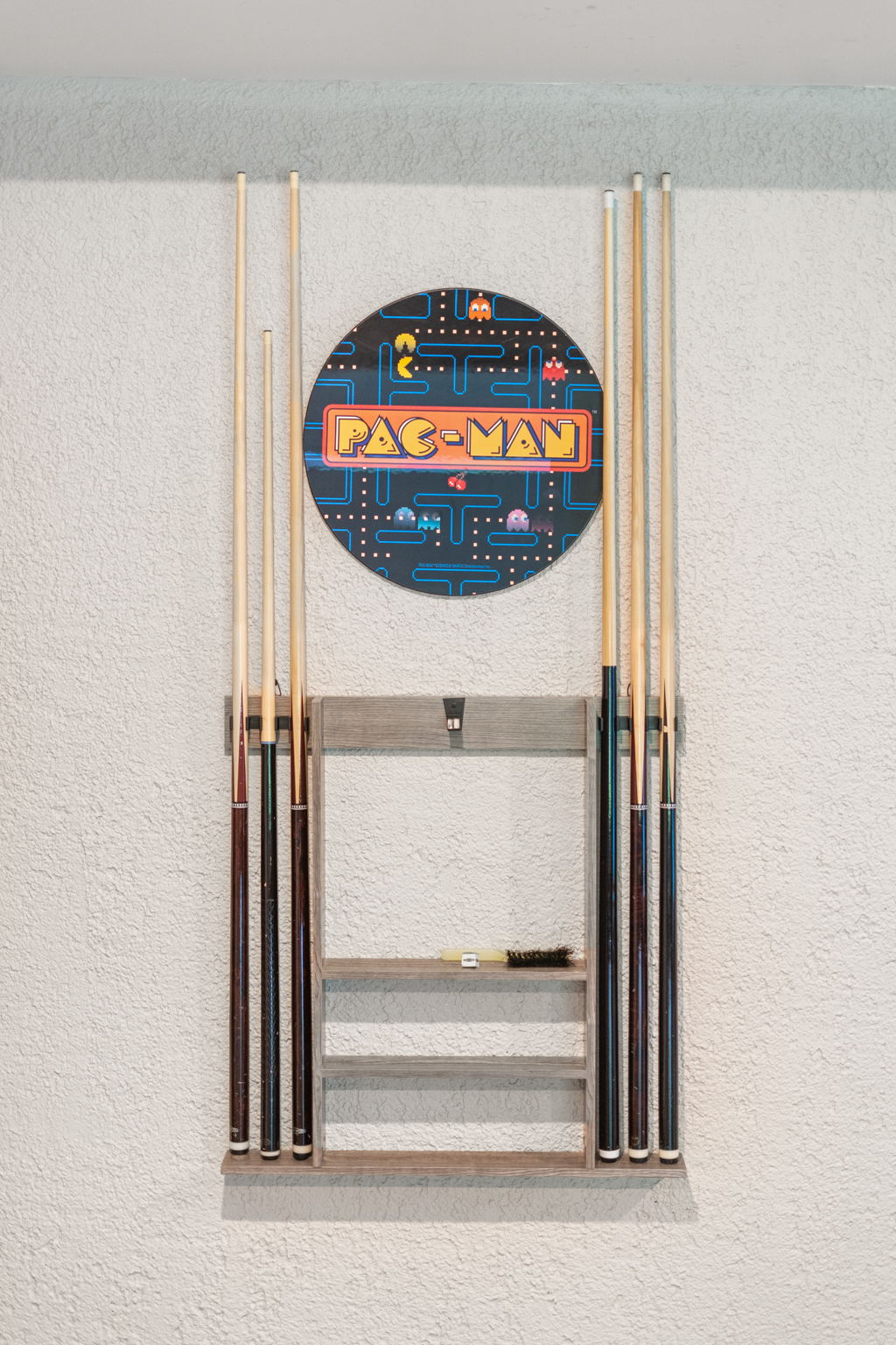 A stylish pool cue rack featuring a PAC-MAN sign and game-themed decor.