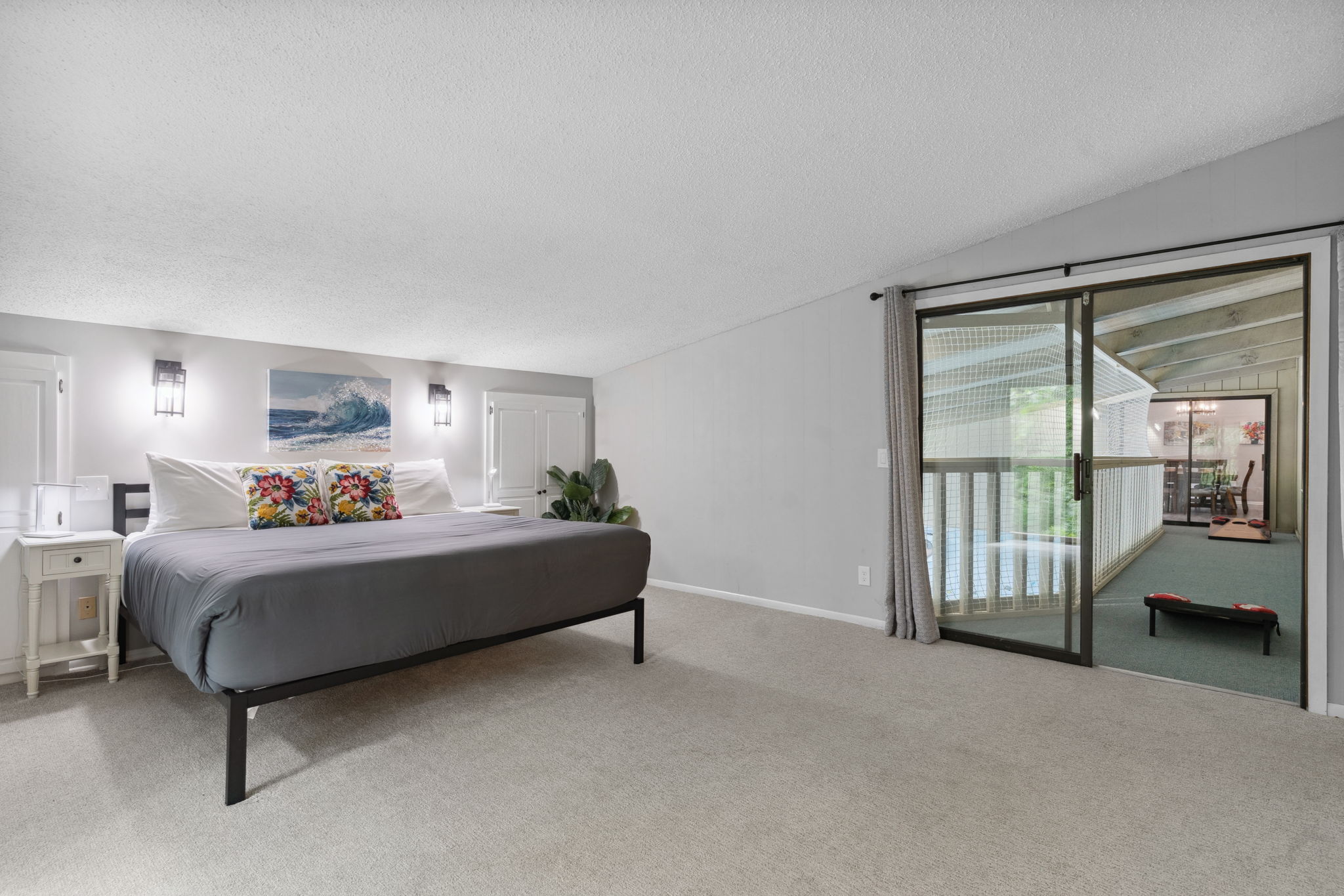 A cozy and modern bedroom featuring a large bed, vibrant pillows, and a glass door leading to a balcony.