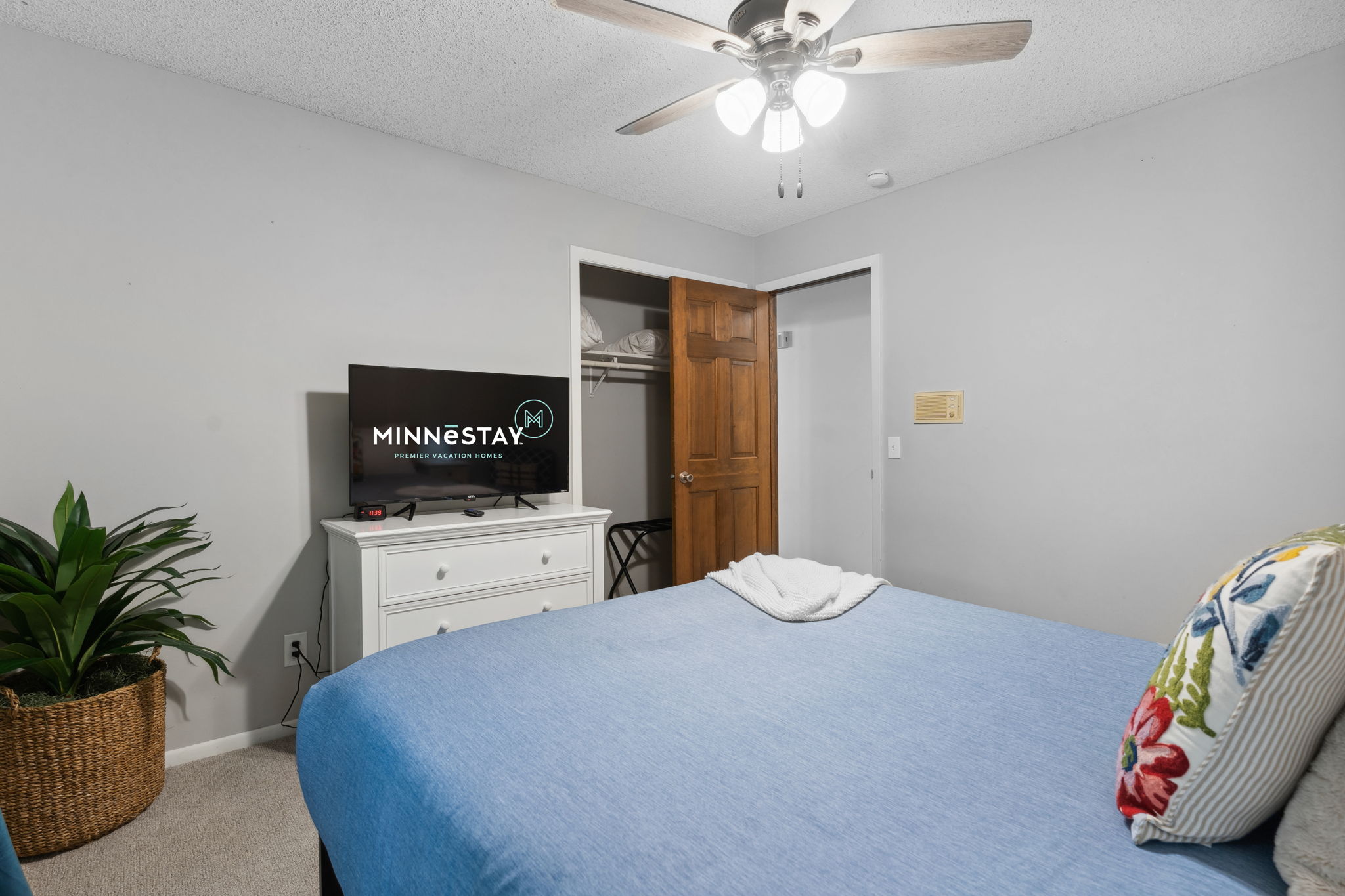 A cozy bedroom with a blue-themed bed, a TV, and decorative elements.