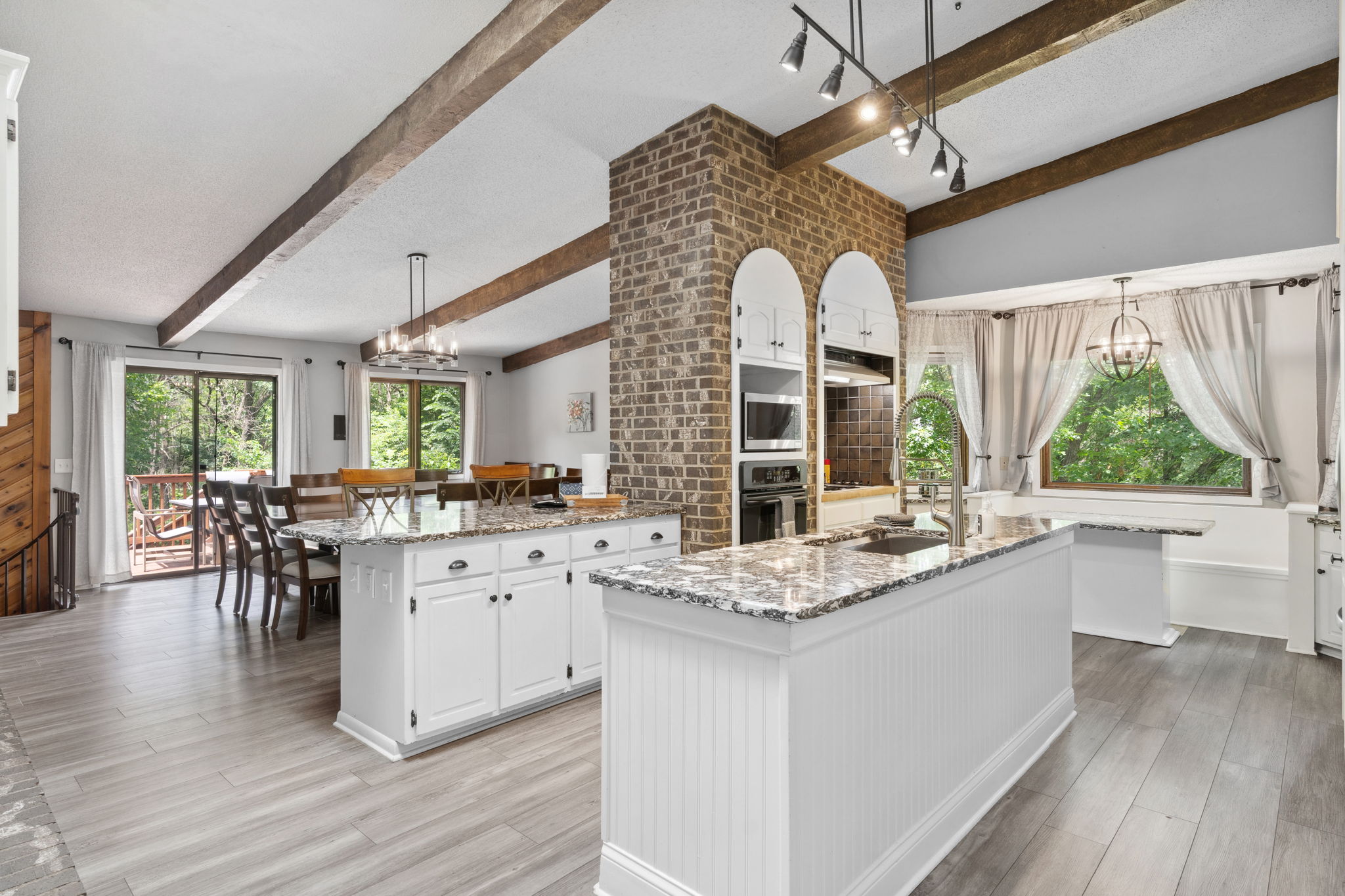 Modern kitchen with white cabinetry, granite countertops, and a brick wall.