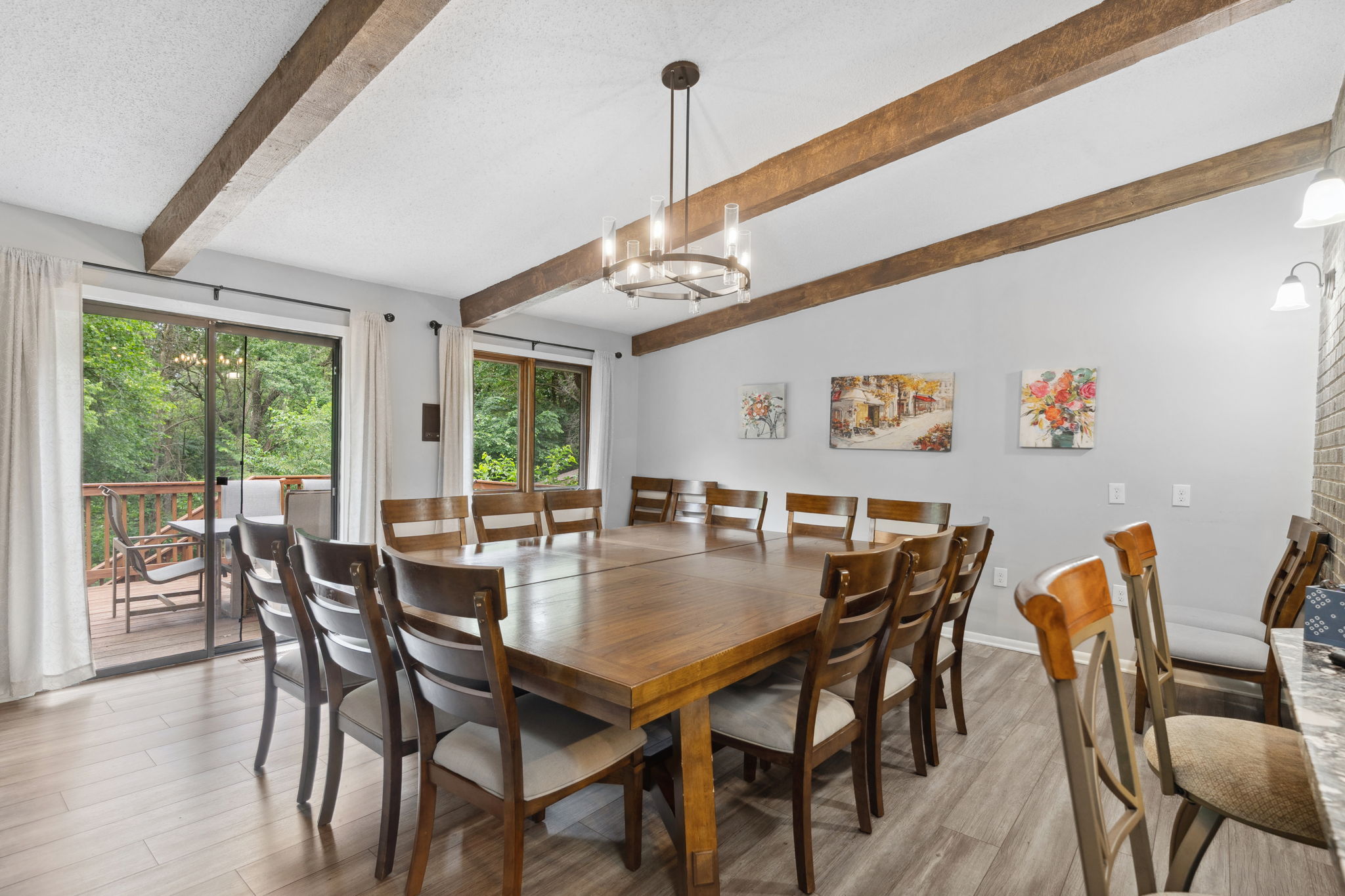 A stylish dining area with a large table and views of lush greenery outside.