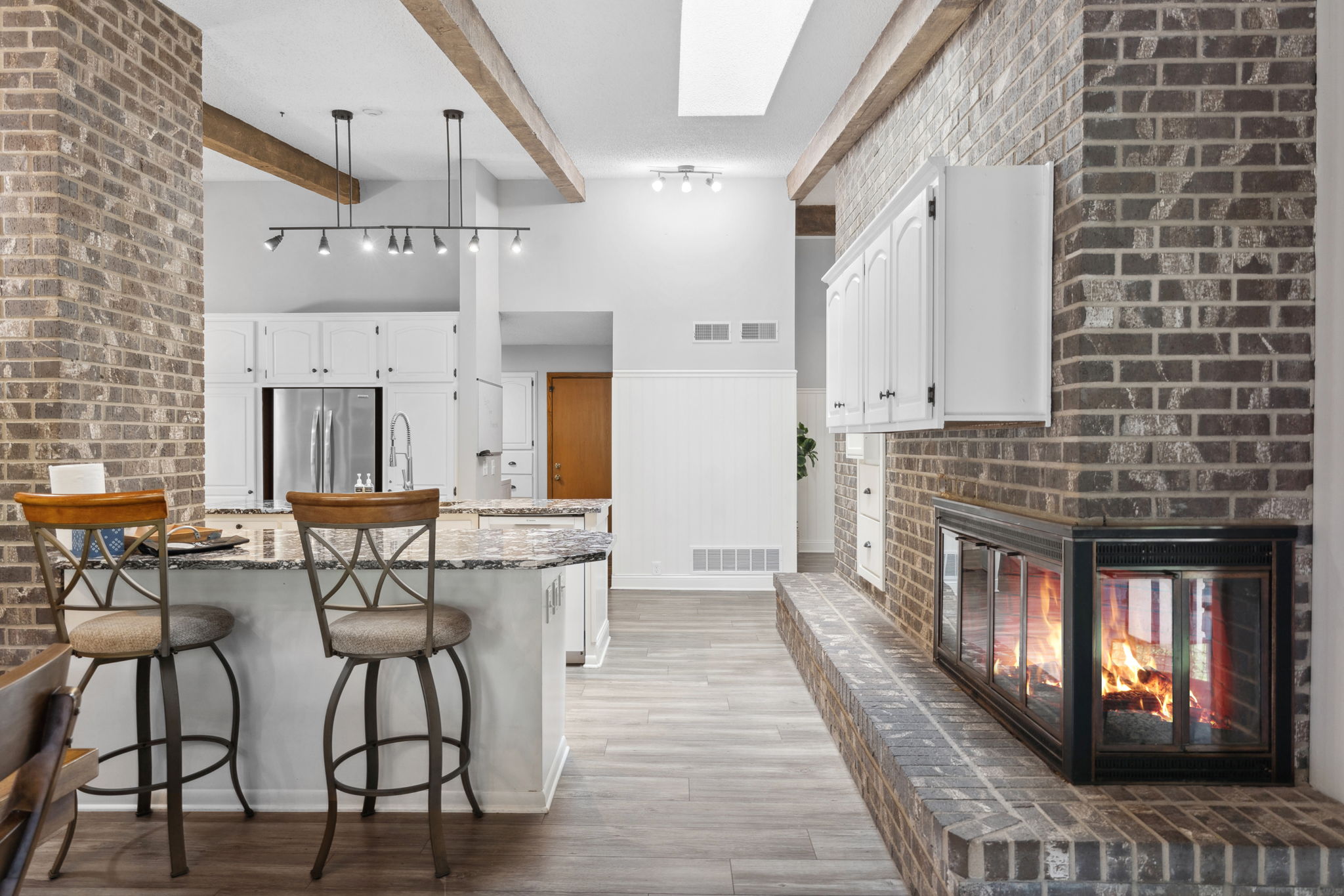 A modern kitchen featuring a stylish island and a warm brick fireplace.