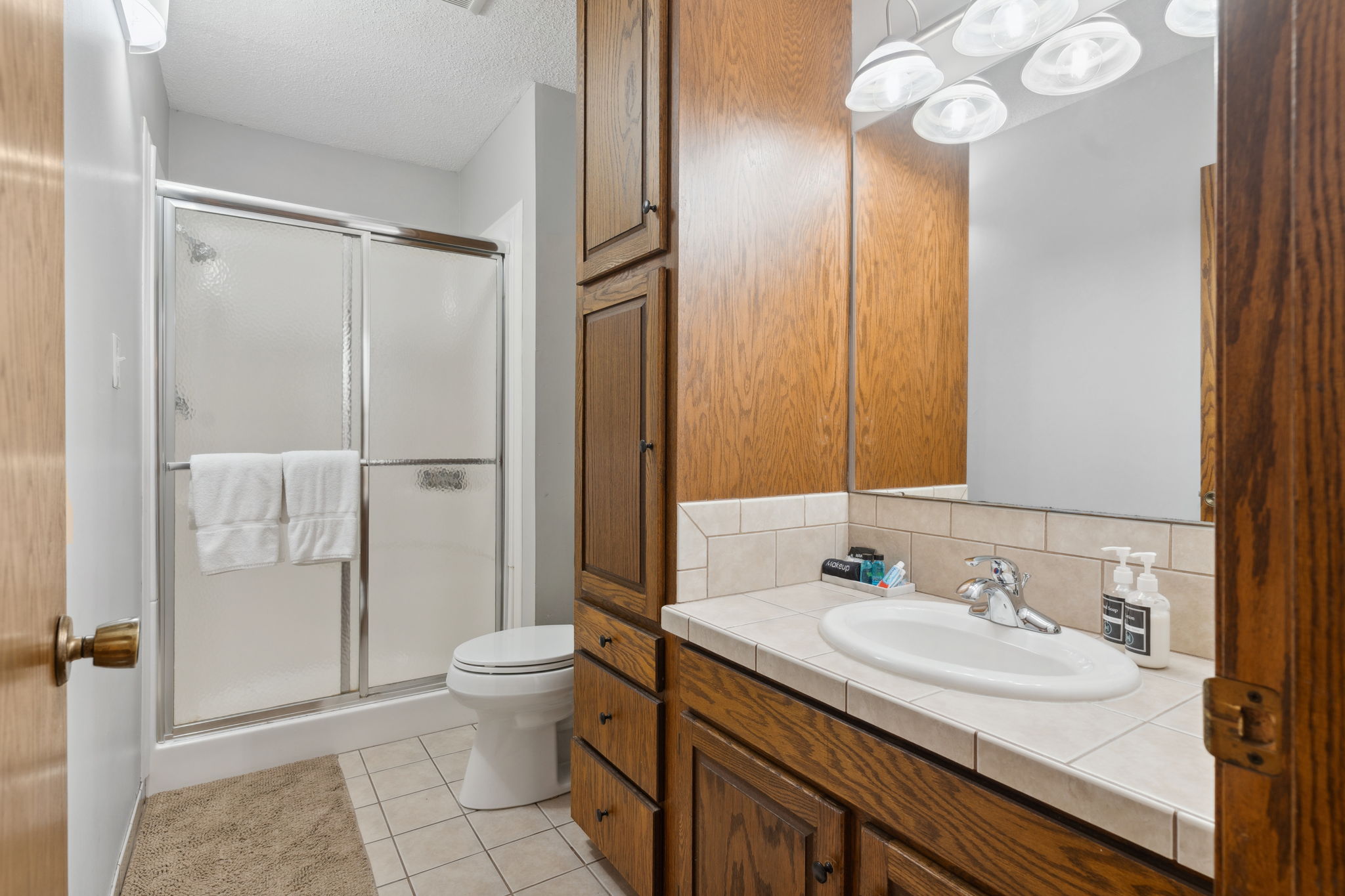 A modern bathroom featuring a wooden vanity and glass shower enclosure.