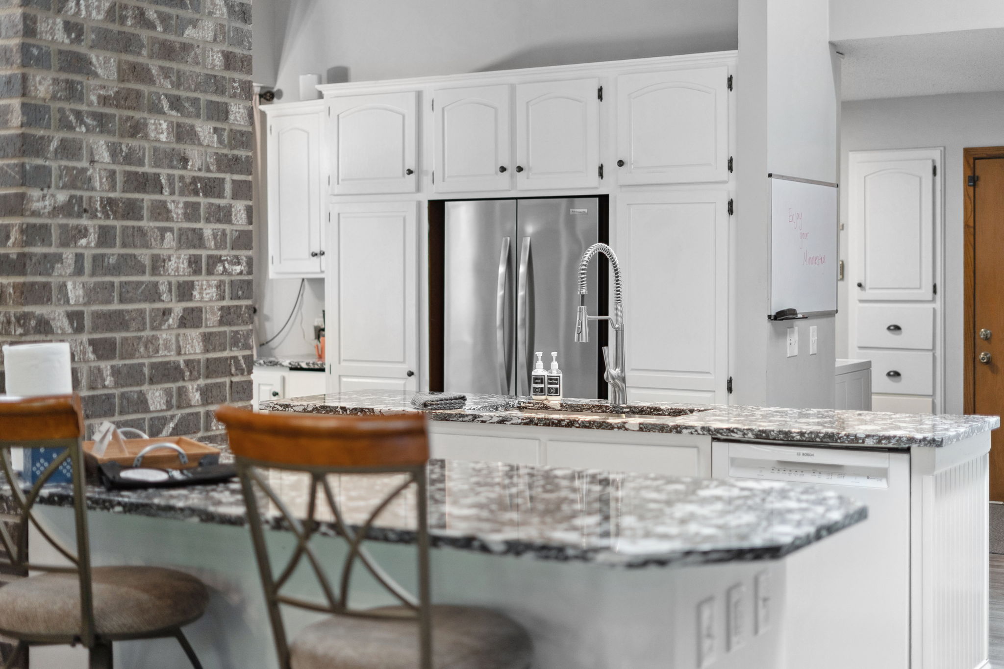 A modern kitchen featuring a stylish island and rustic wall.