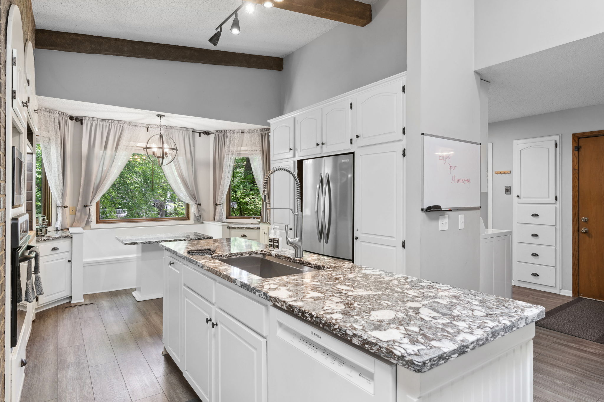 A cozy modern kitchen with granite countertops and large windows.