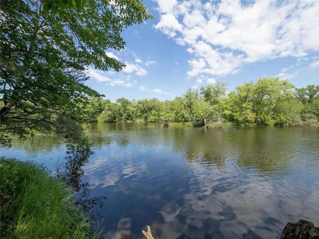 A peaceful river scene surrounded by lush greenery and a clear sky.