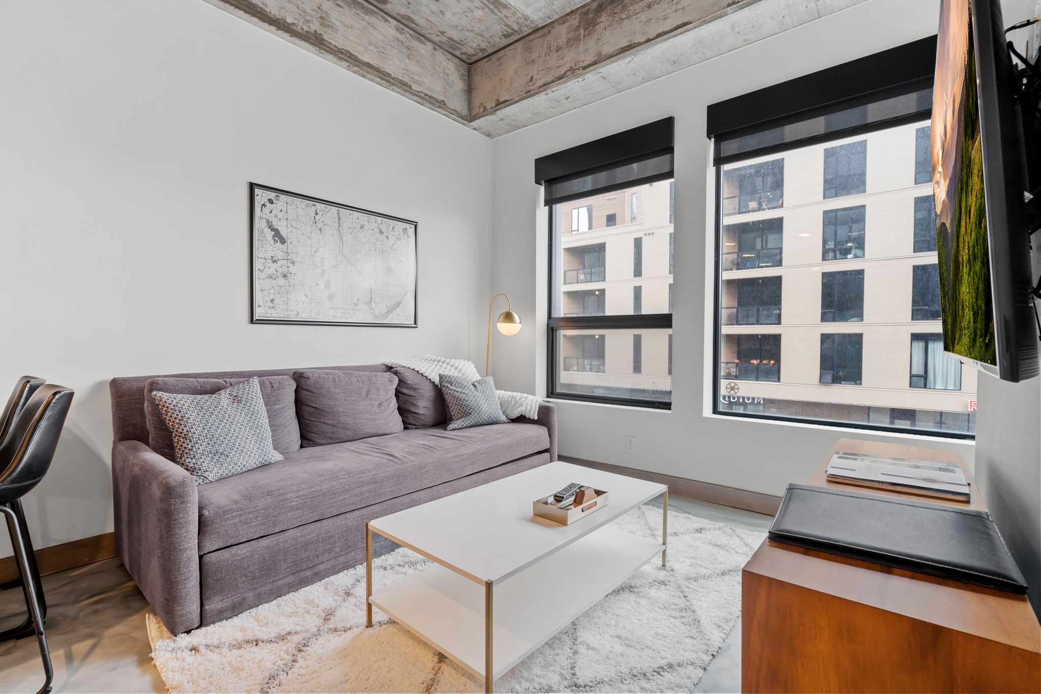 Modern living room with gray sofa, coffee table, and large windows.
