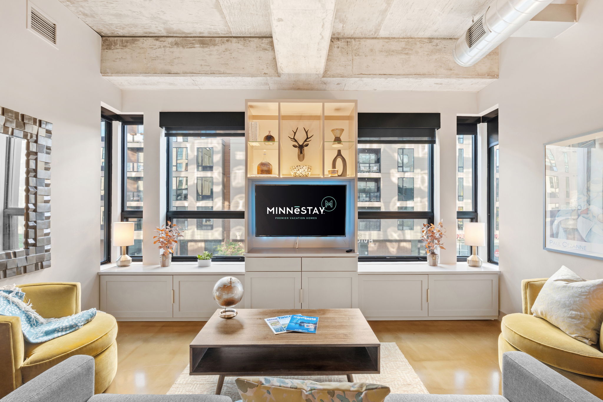 Modern living room with large windows, a TV unit, and decorative elements.