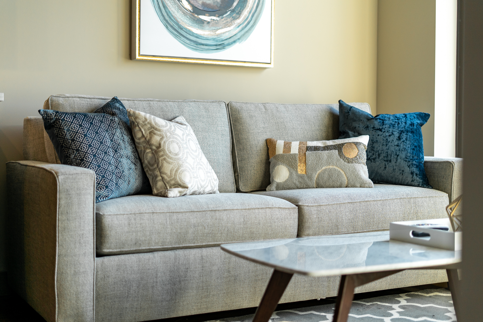 A stylish living room featuring a gray sofa with decorative pillows and modern art.