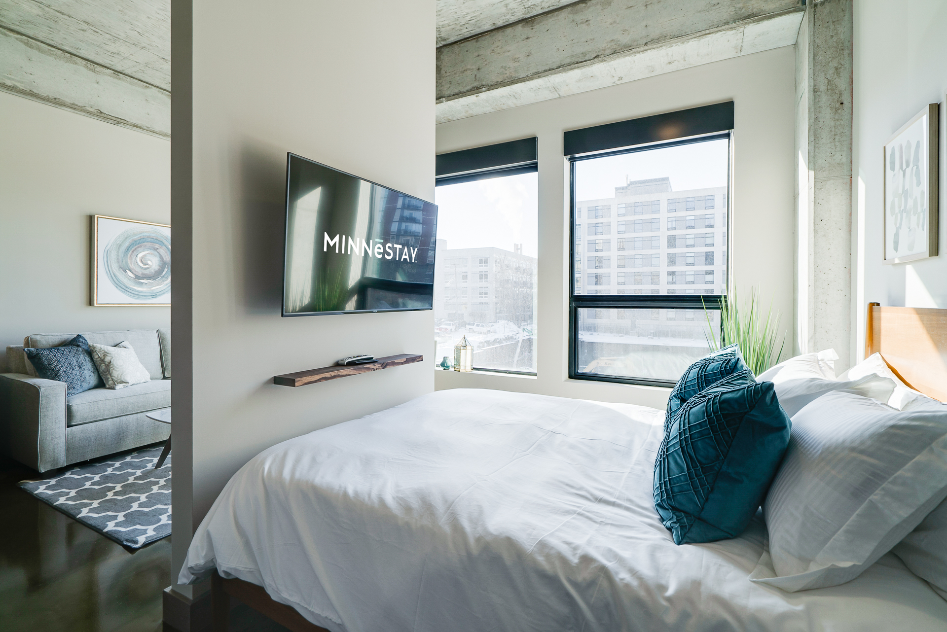 A modern bedroom featuring a sleek bed and stylish decor, illuminated by natural light.