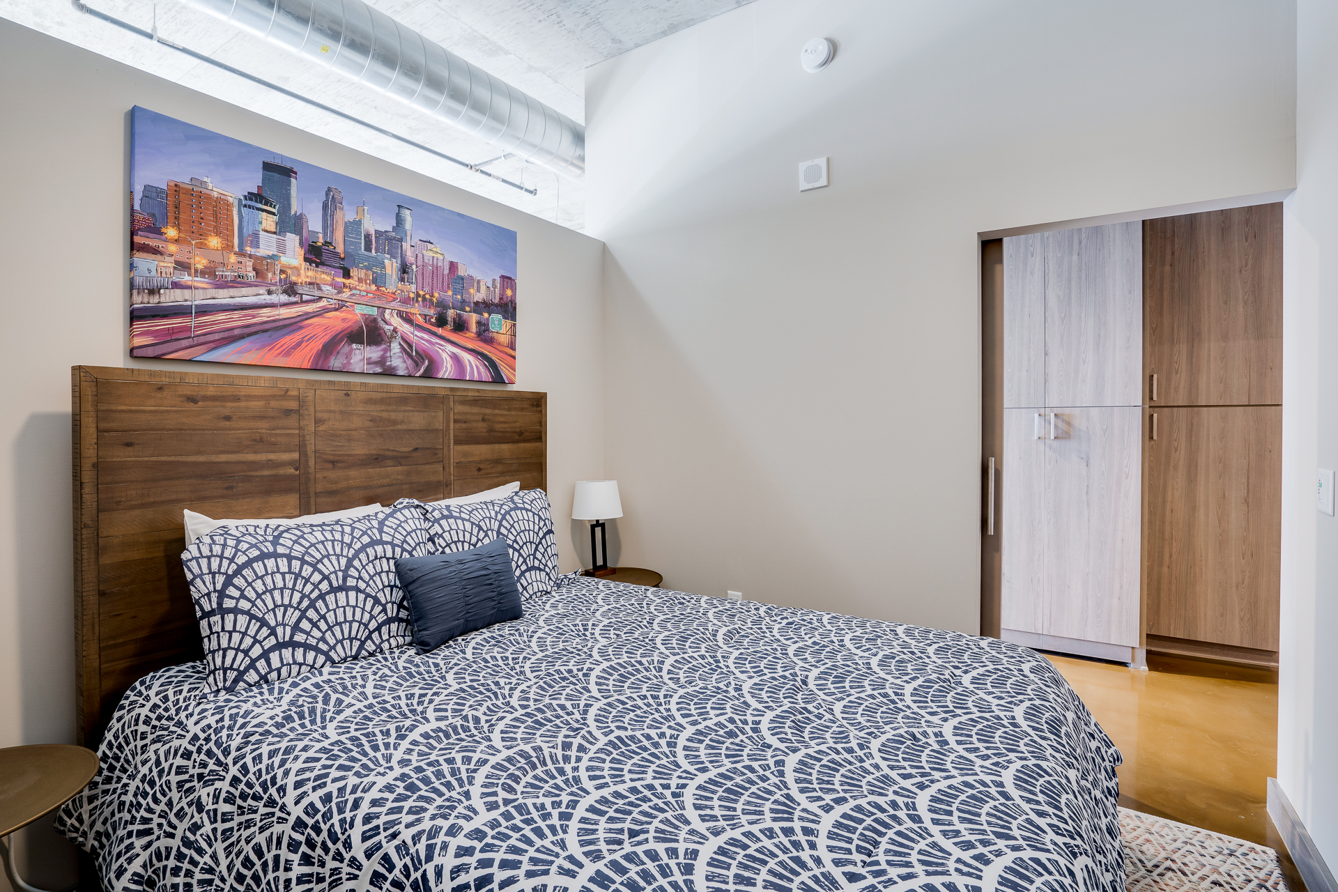 A modern bedroom with a cozy atmosphere and cityscape art.