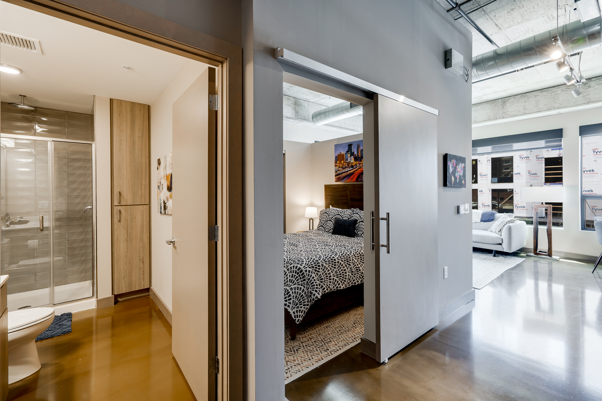 A stylish modern bedroom with adjacent bathroom and living area.