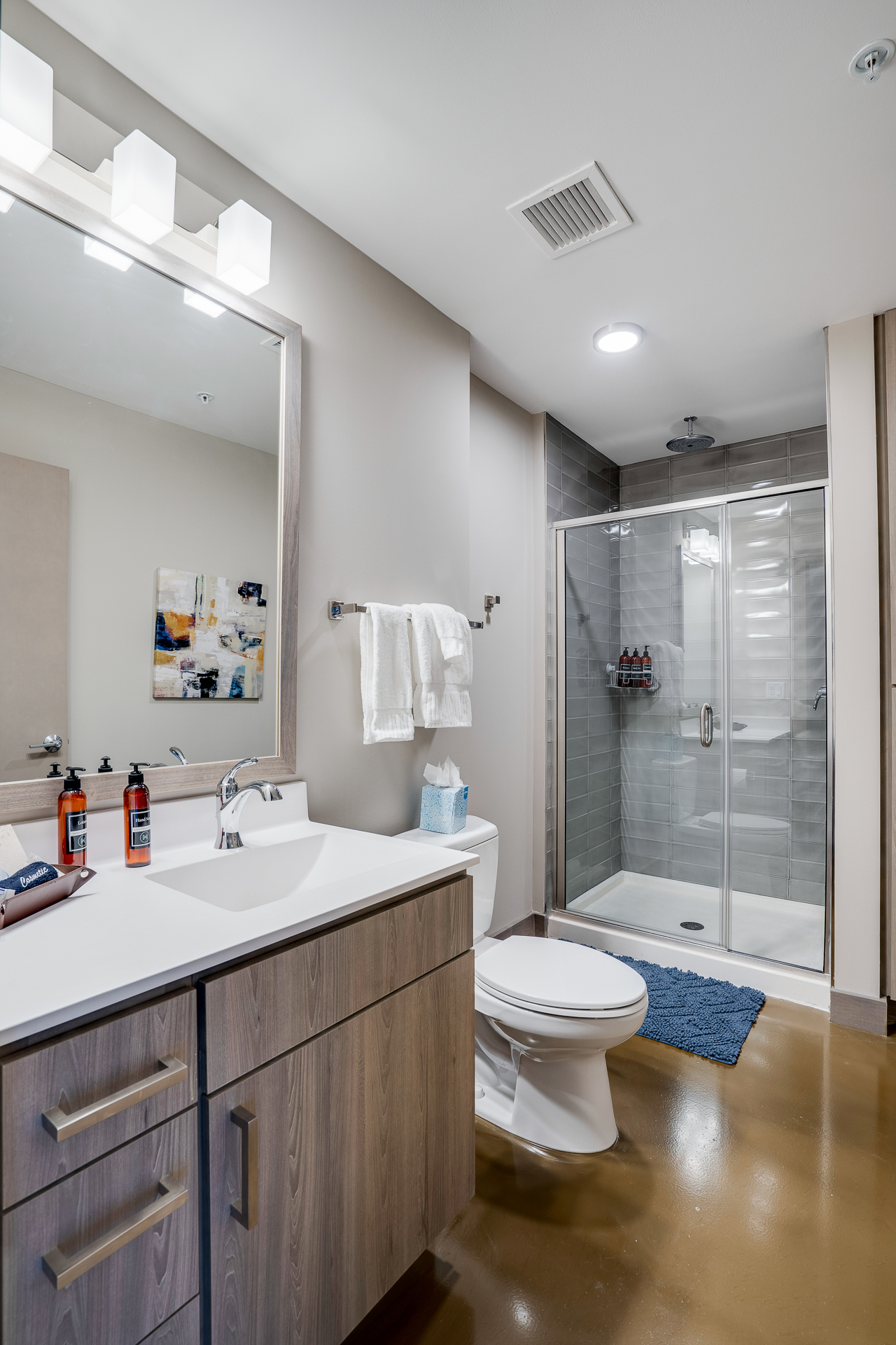 A stylish and modern bathroom with a glass shower and wooden vanity.